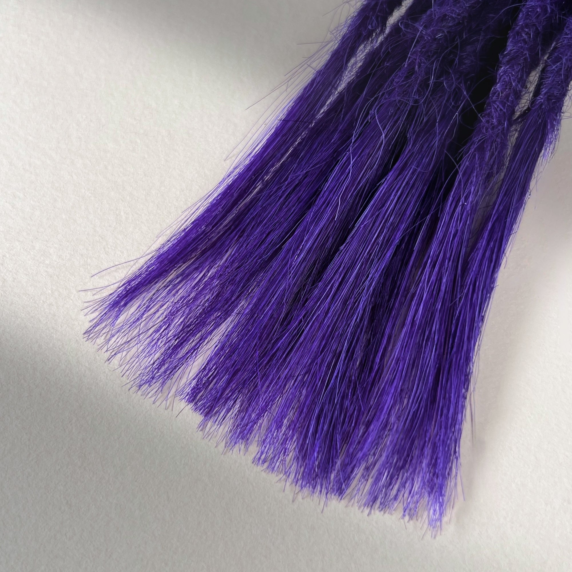 Tip detail of straight loc extensions with open ends in Orchid Violet.