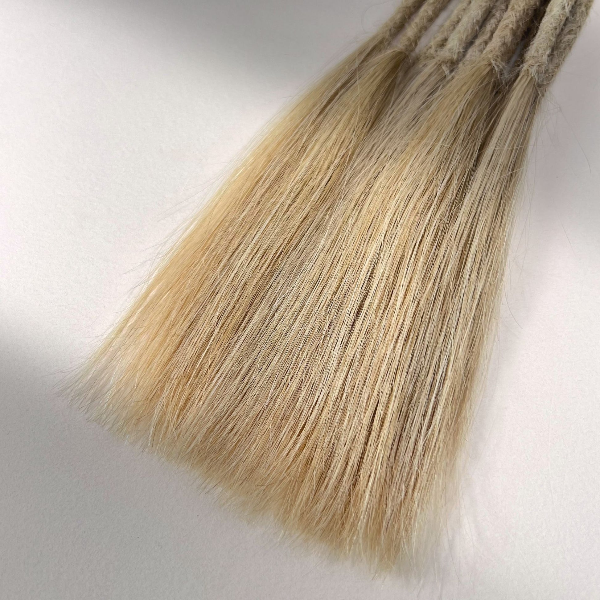 Tip detail of straight loc extensions with long loose ends in Cream Blonde.