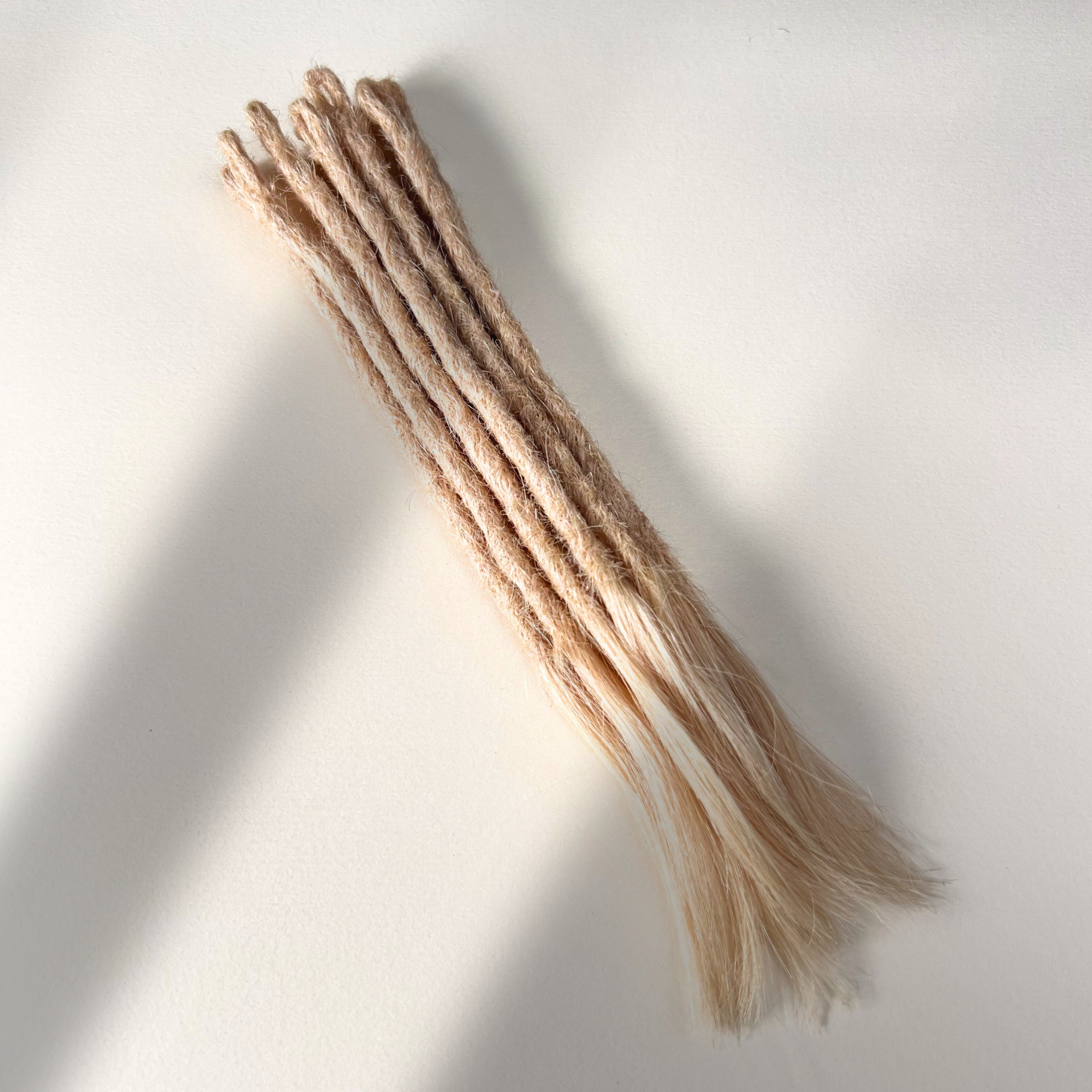 Full view of temporary single-ended straight loc extensions with open ends in Soft Rose Blonde.