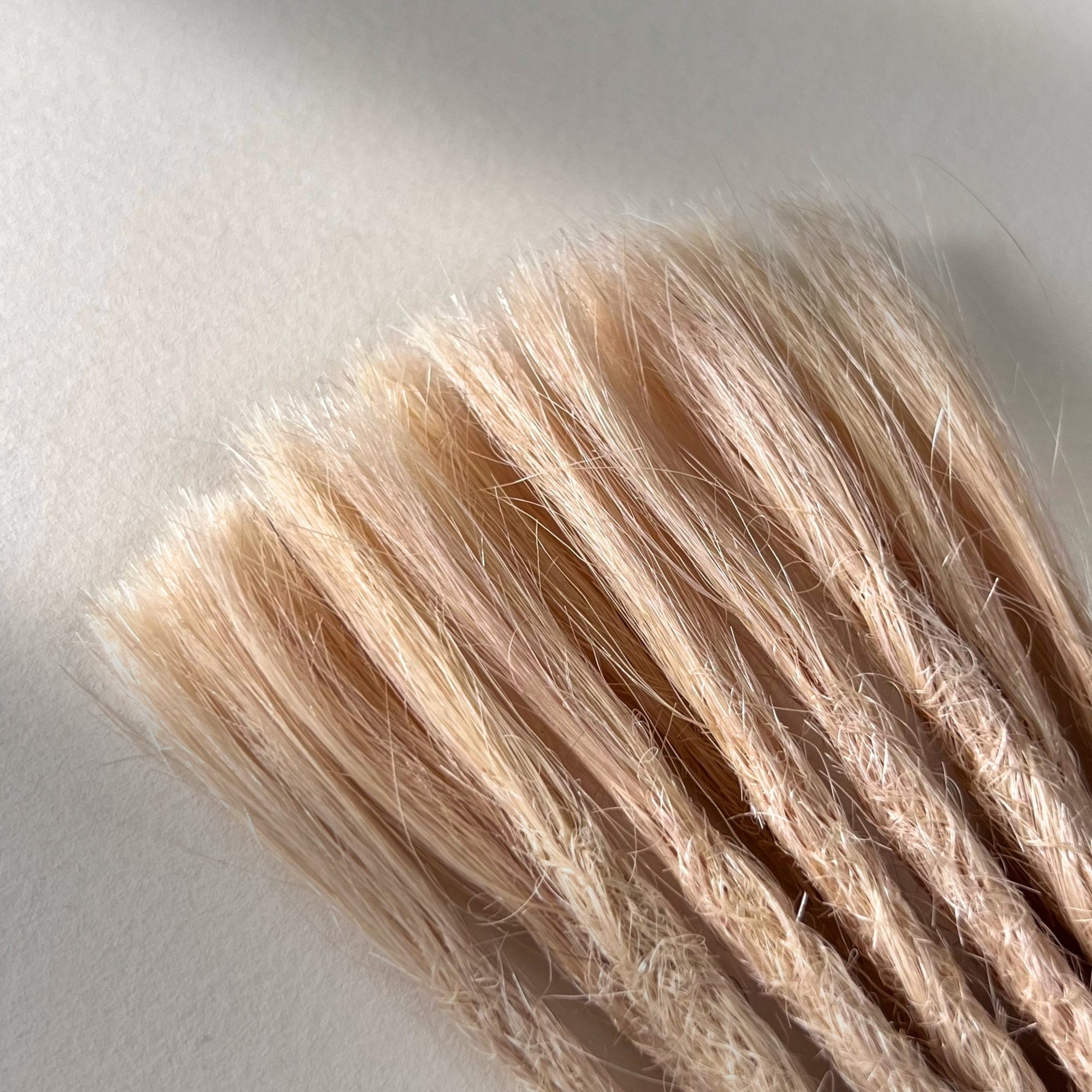 Connection point of permanent straight loc extensions in Soft Rose Blonde.