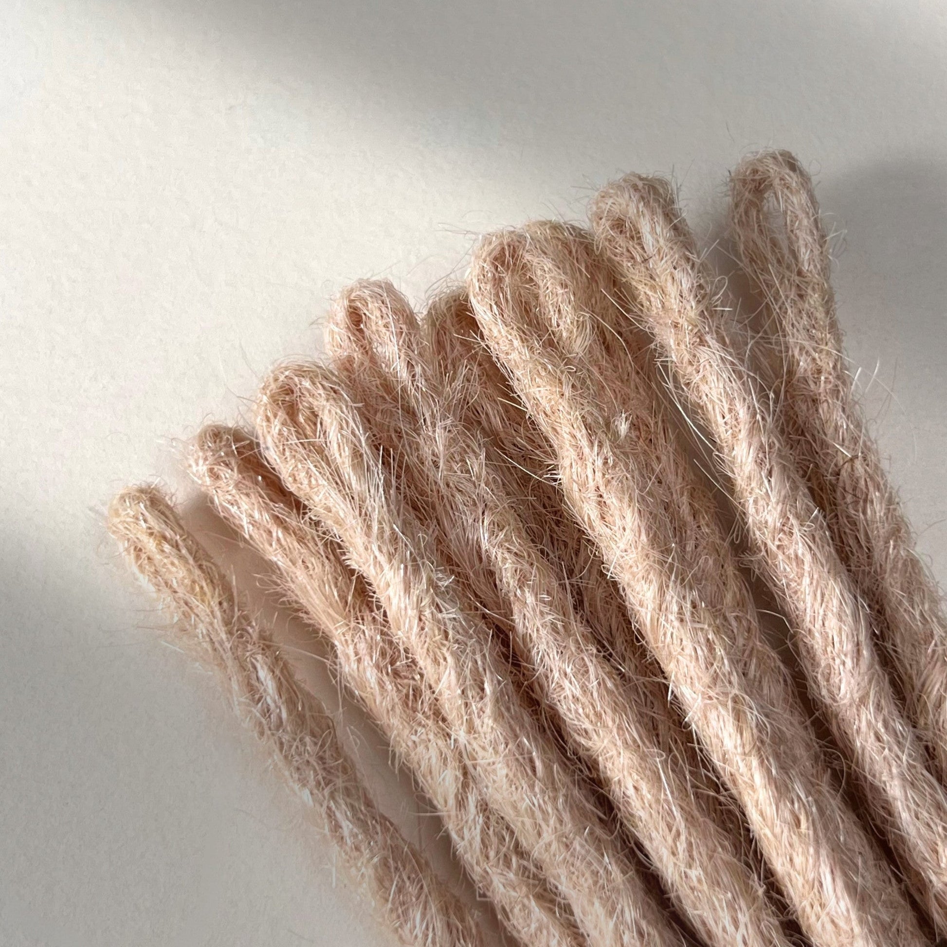 Loop detail of temporary single-ended straight loc extensions in Soft Rose Blonde.