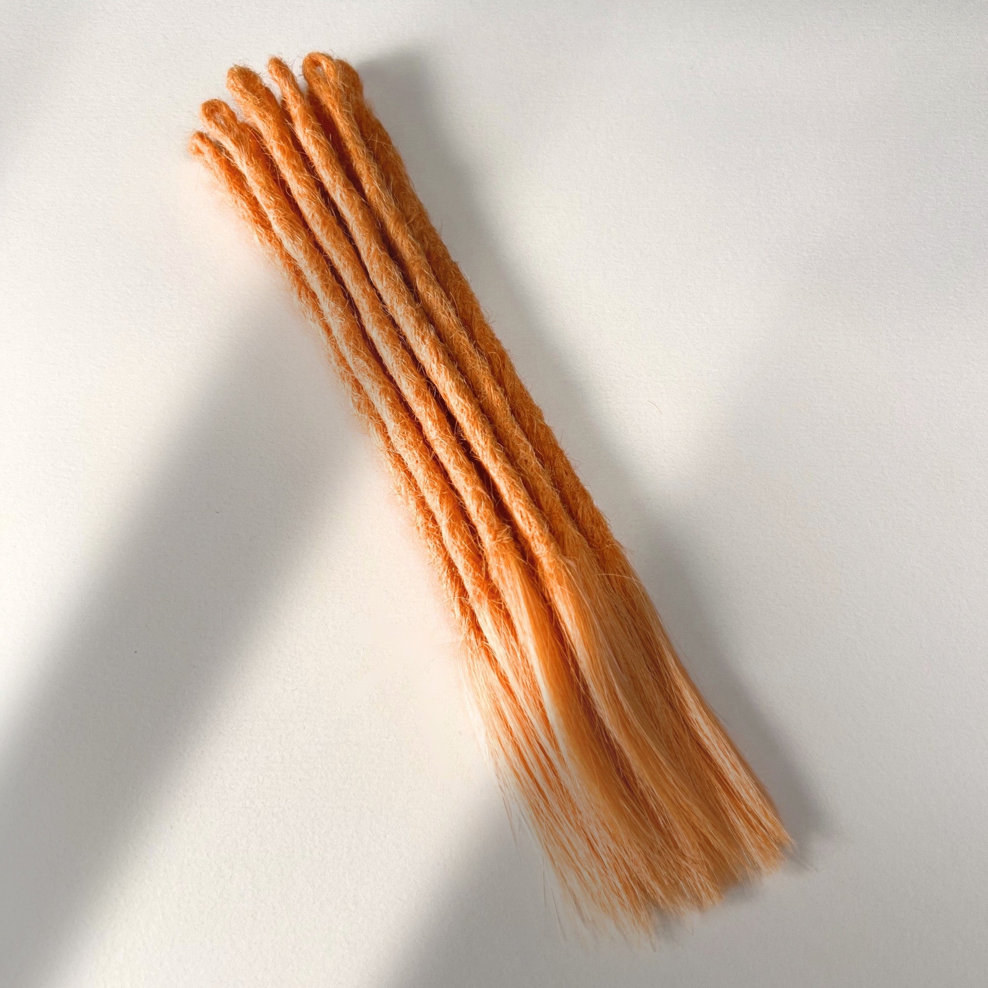 Full view of temporary single-ended straight loc extensions with open ends in Peach Orange.
