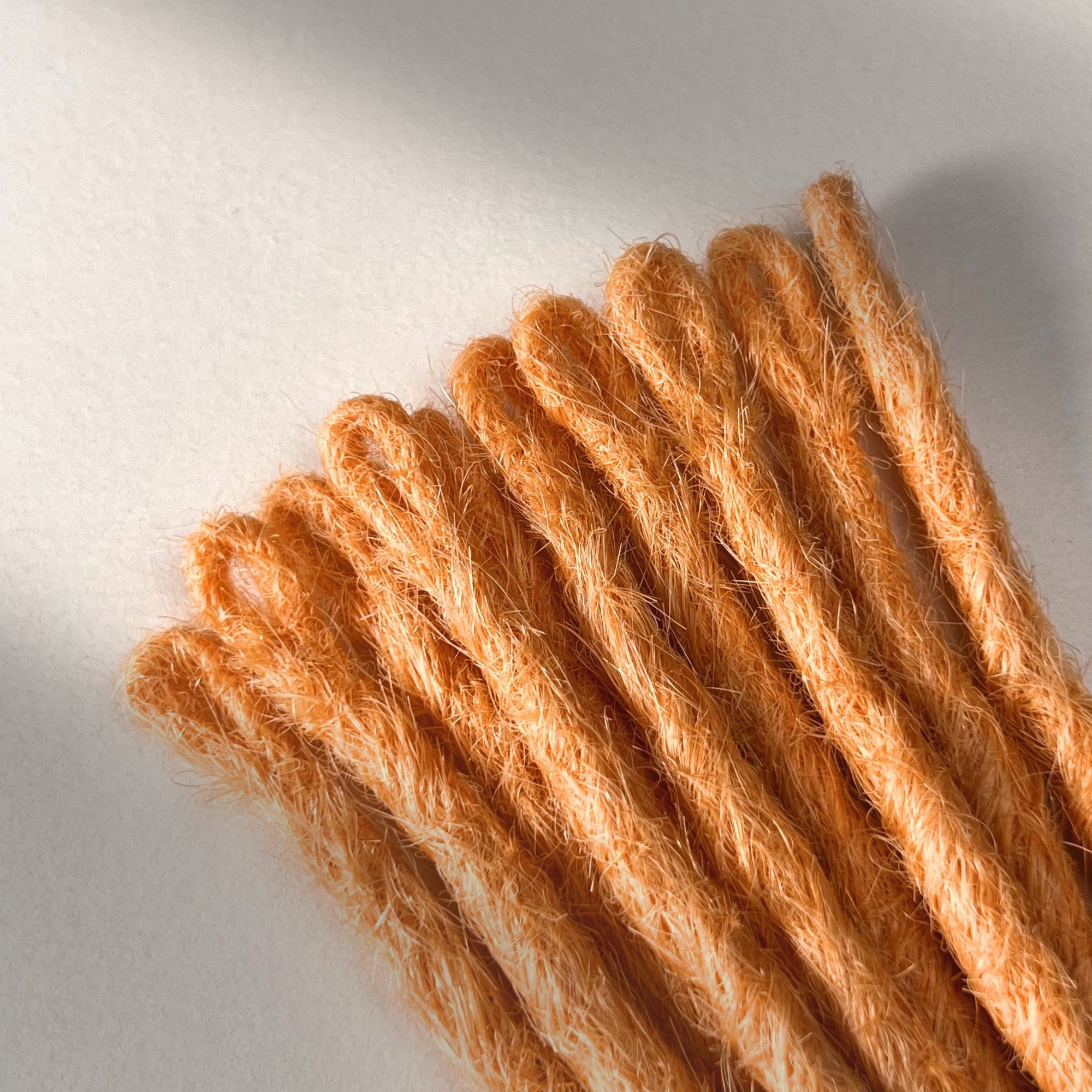 Loop detail of temporary single-ended straight loc extensions in Peach Orange.