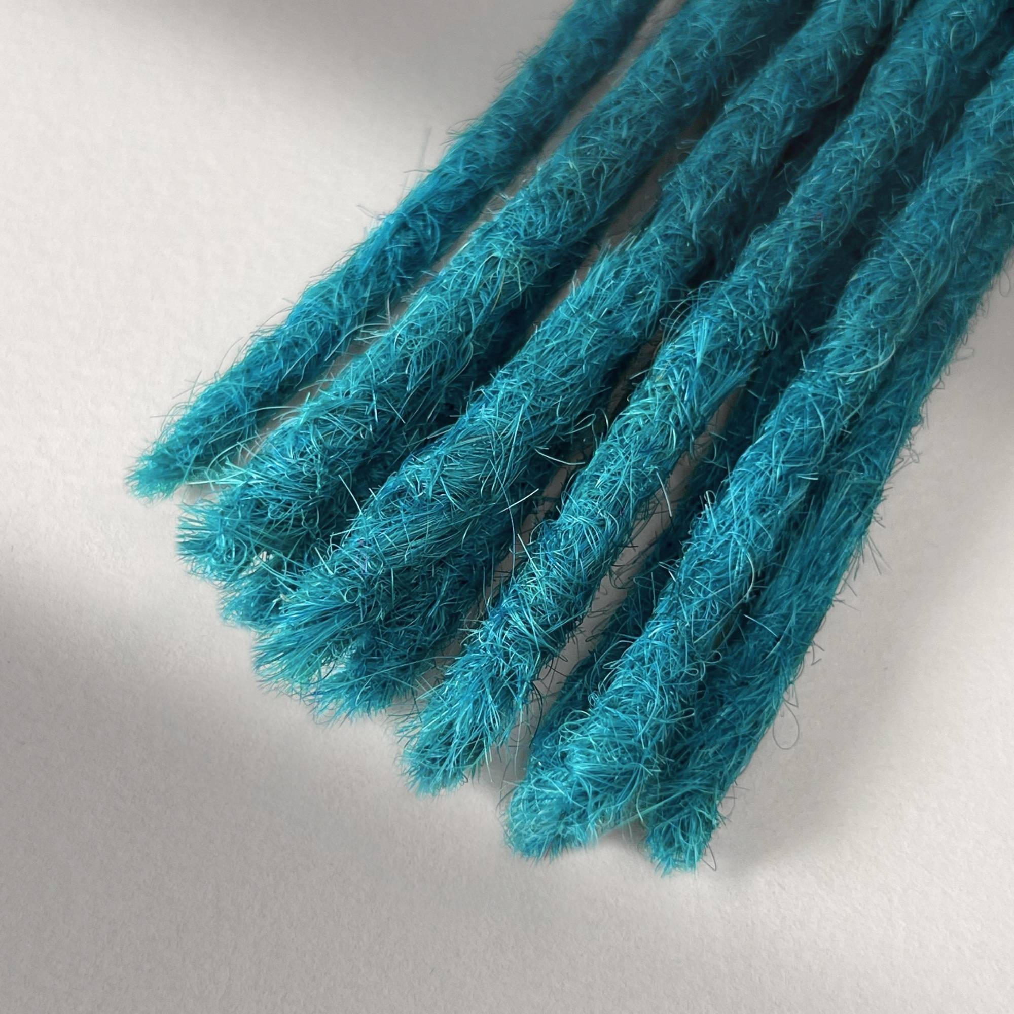 Tip detail of straight loc extensions with blunt ends in Frost Blue.