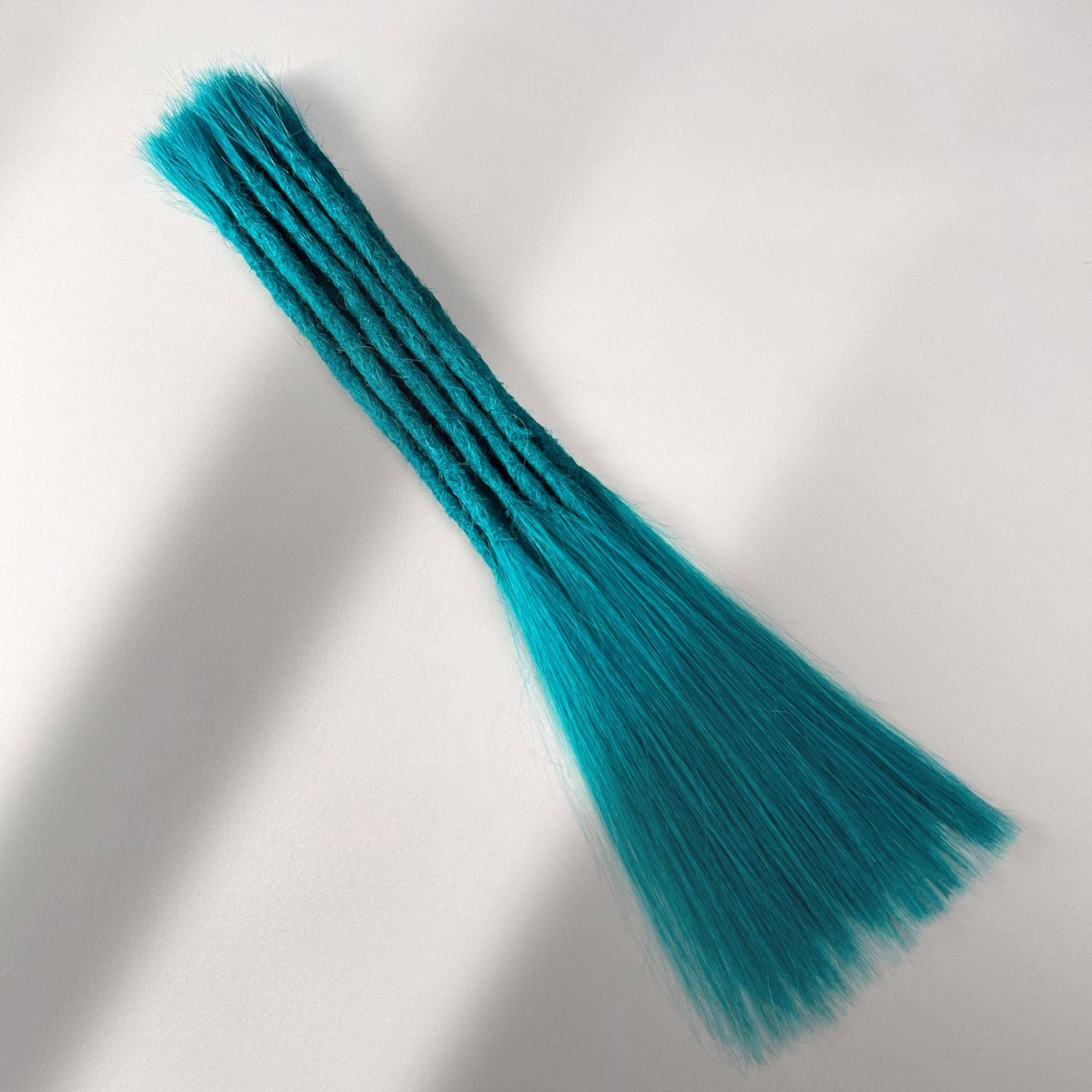 Full view of permanent straight loc extensions with long loose ends in Frost Blue.