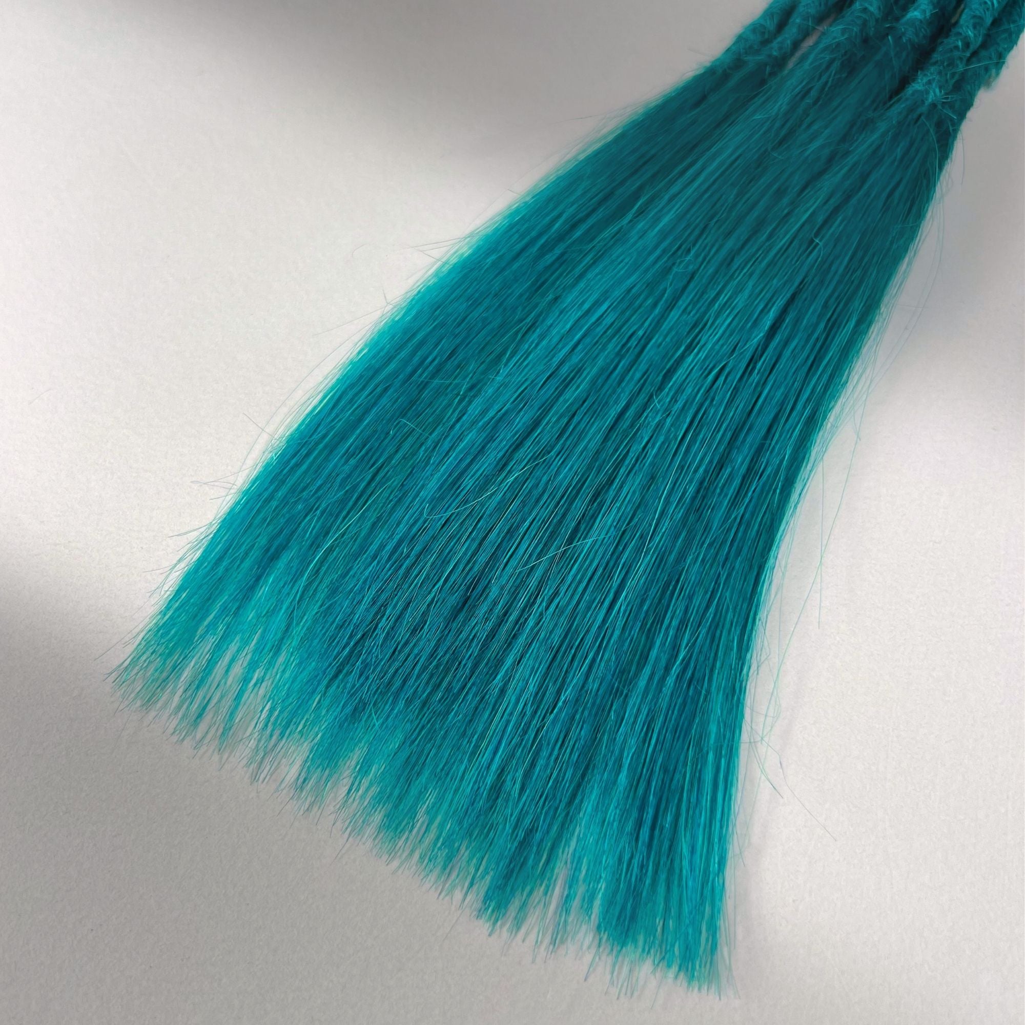 Tip detail of straight loc extensions with long loose ends in Frost Blue.