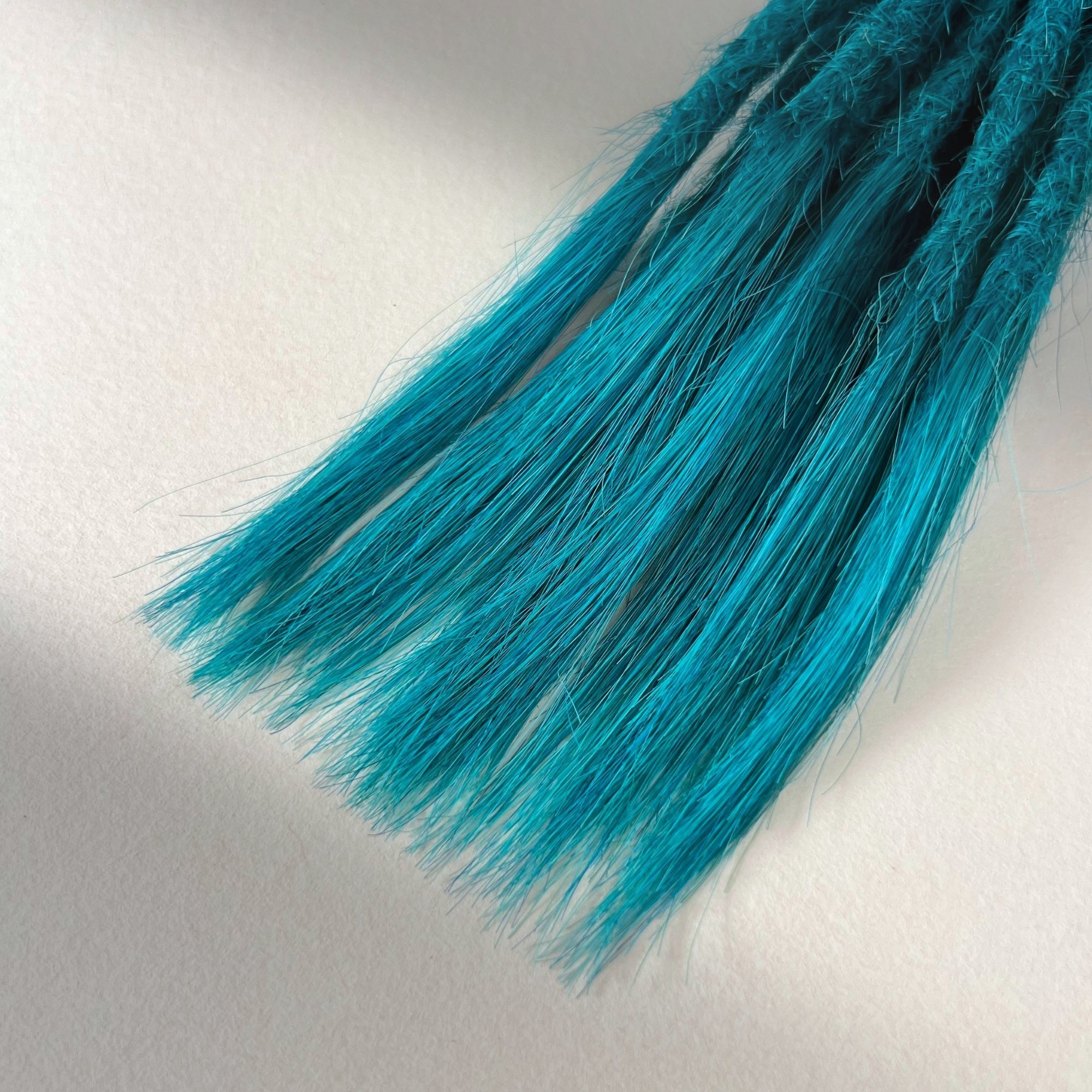 Tip detail of straight loc extensions with open ends in Frost Blue.