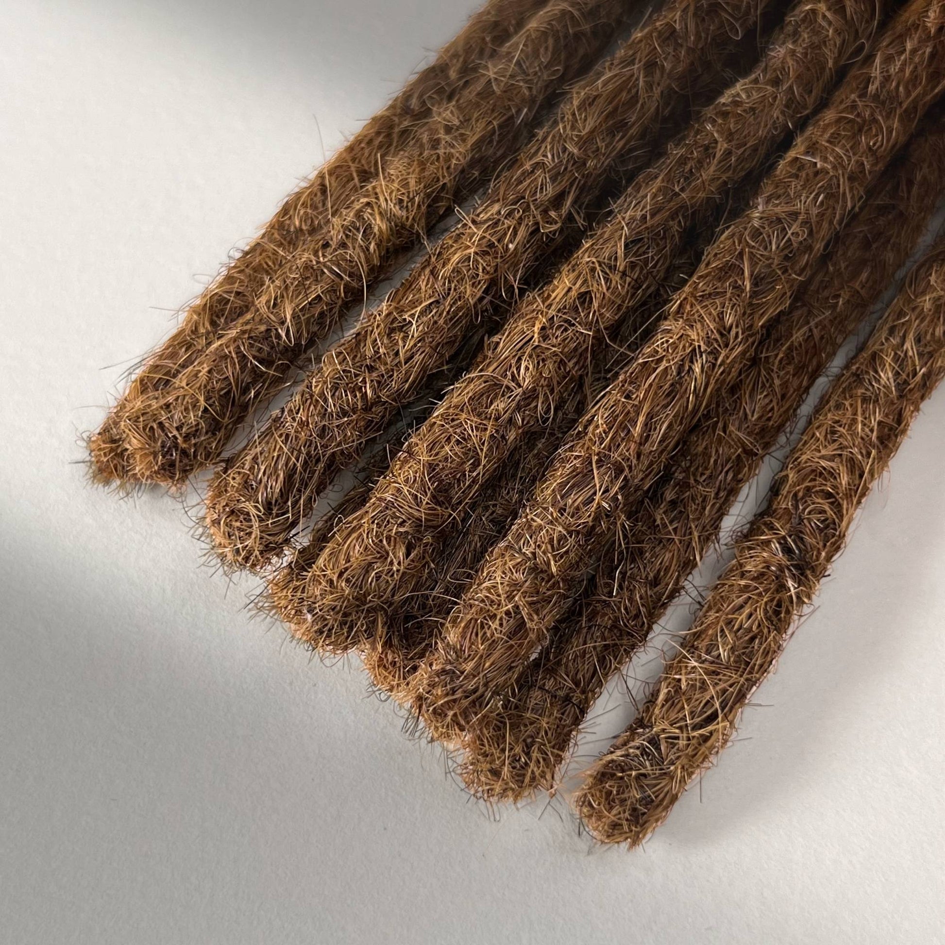 Tip detail of straight loc extensions with blunt ends in Warm Chestnut Brown.
