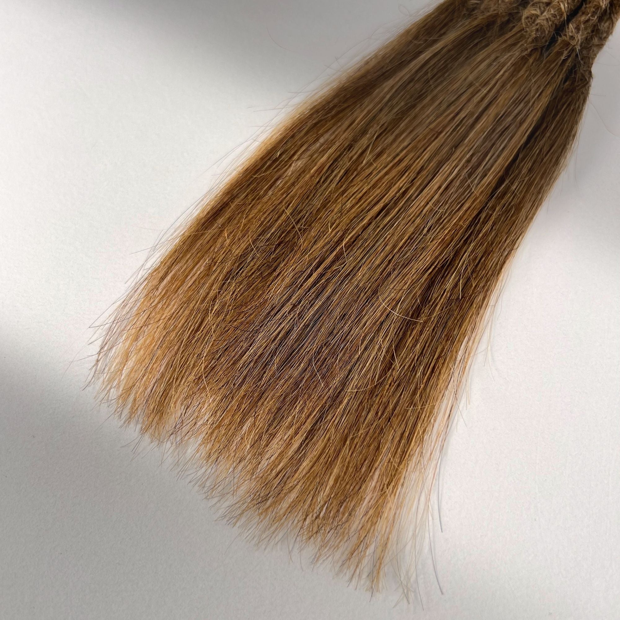 Tip detail of straight loc extensions with long loose ends in Warm Chestnut Brown.