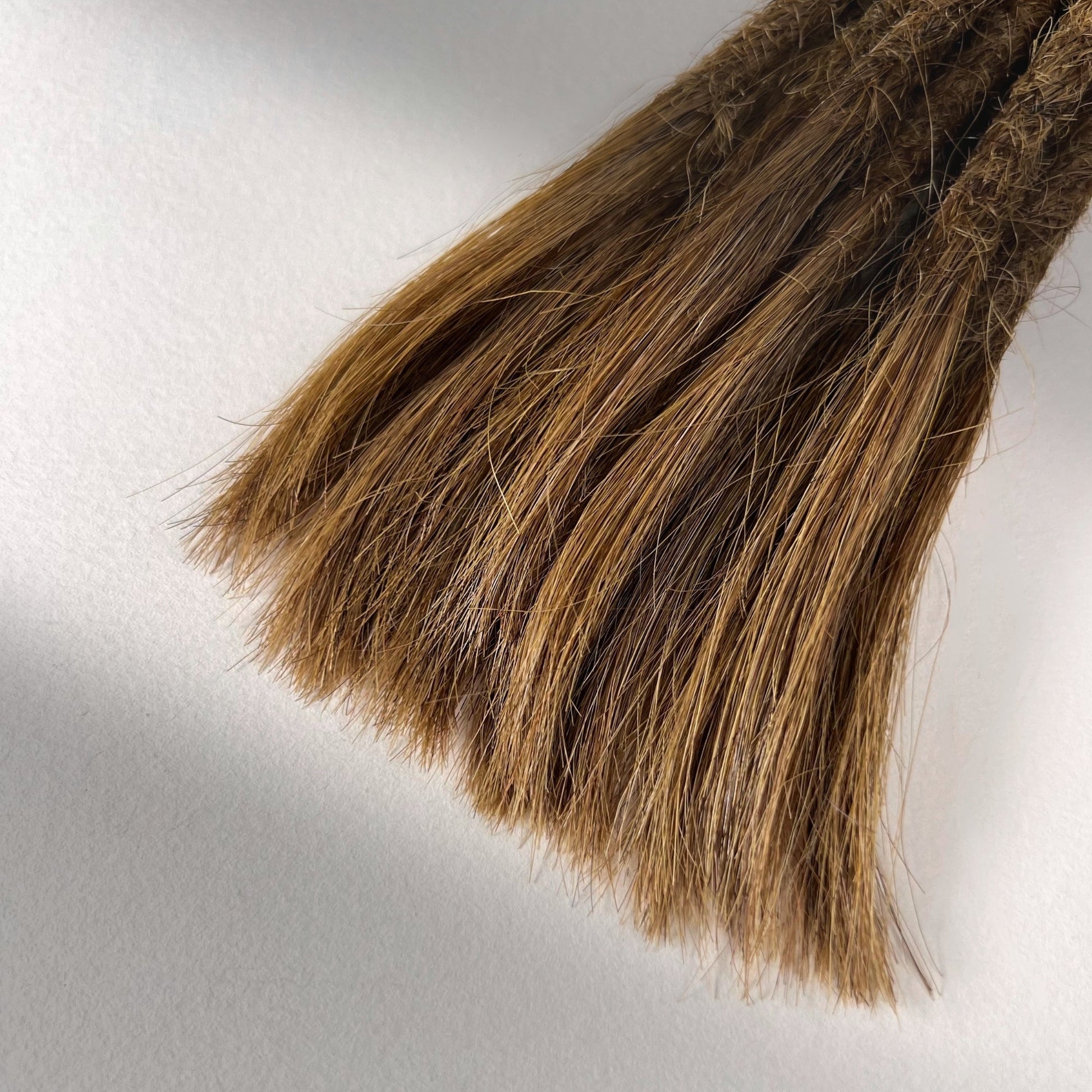 Tip detail of straight loc extensions with open ends in Warm Chestnut Brown.