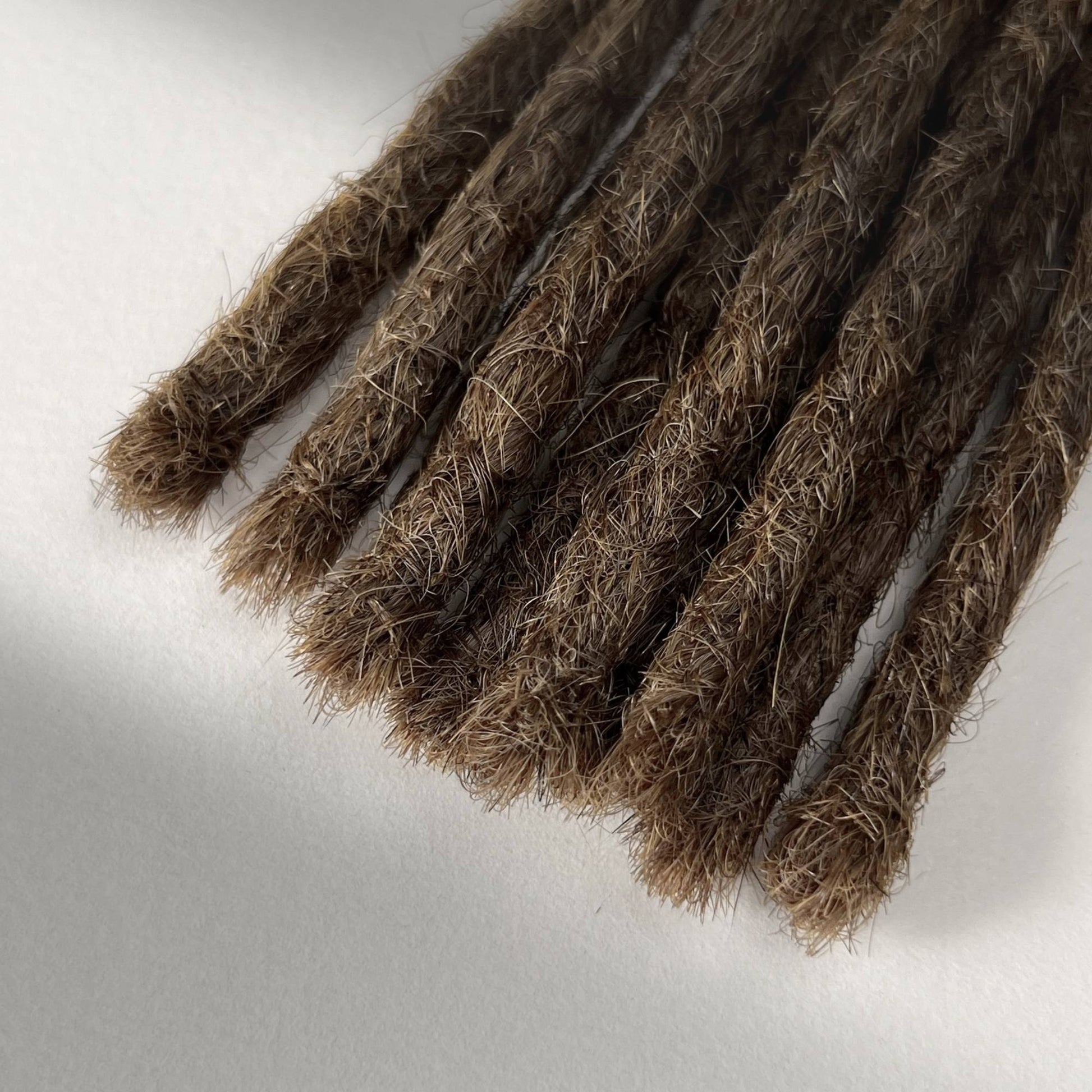 Tip detail of straight loc extensions with blunt ends in Natural Medium Brown.