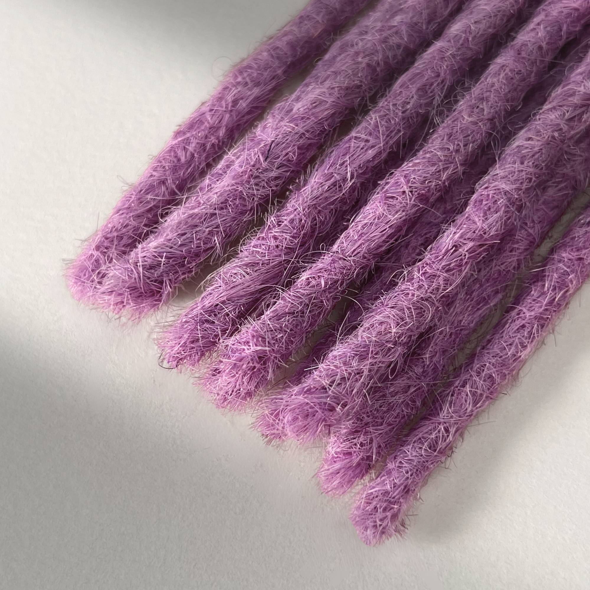 Tip detail of straight loc extensions with blunt ends in Lavender Purple.