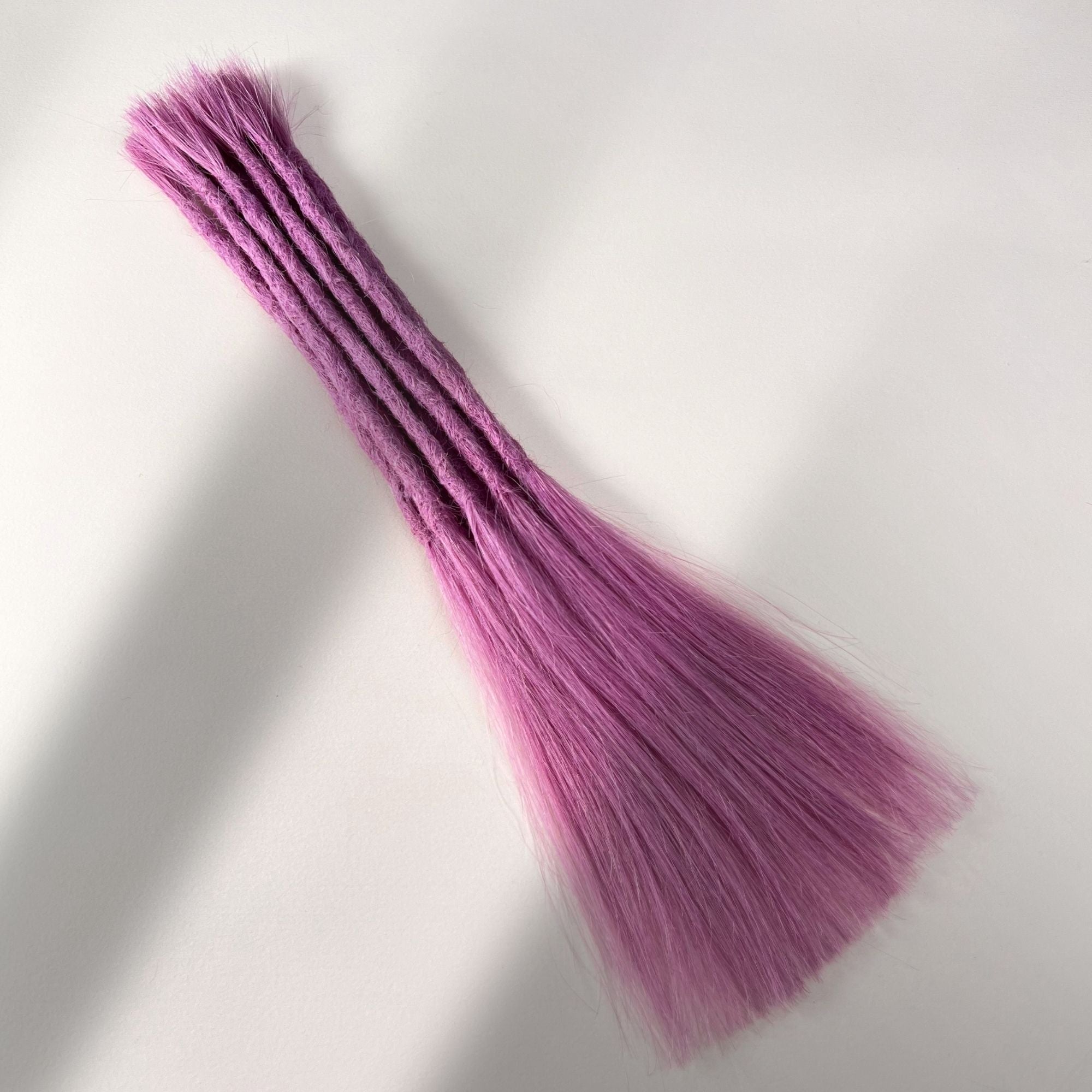 Full view of permanent straight loc extensions with long loose ends in Lavender Purple.