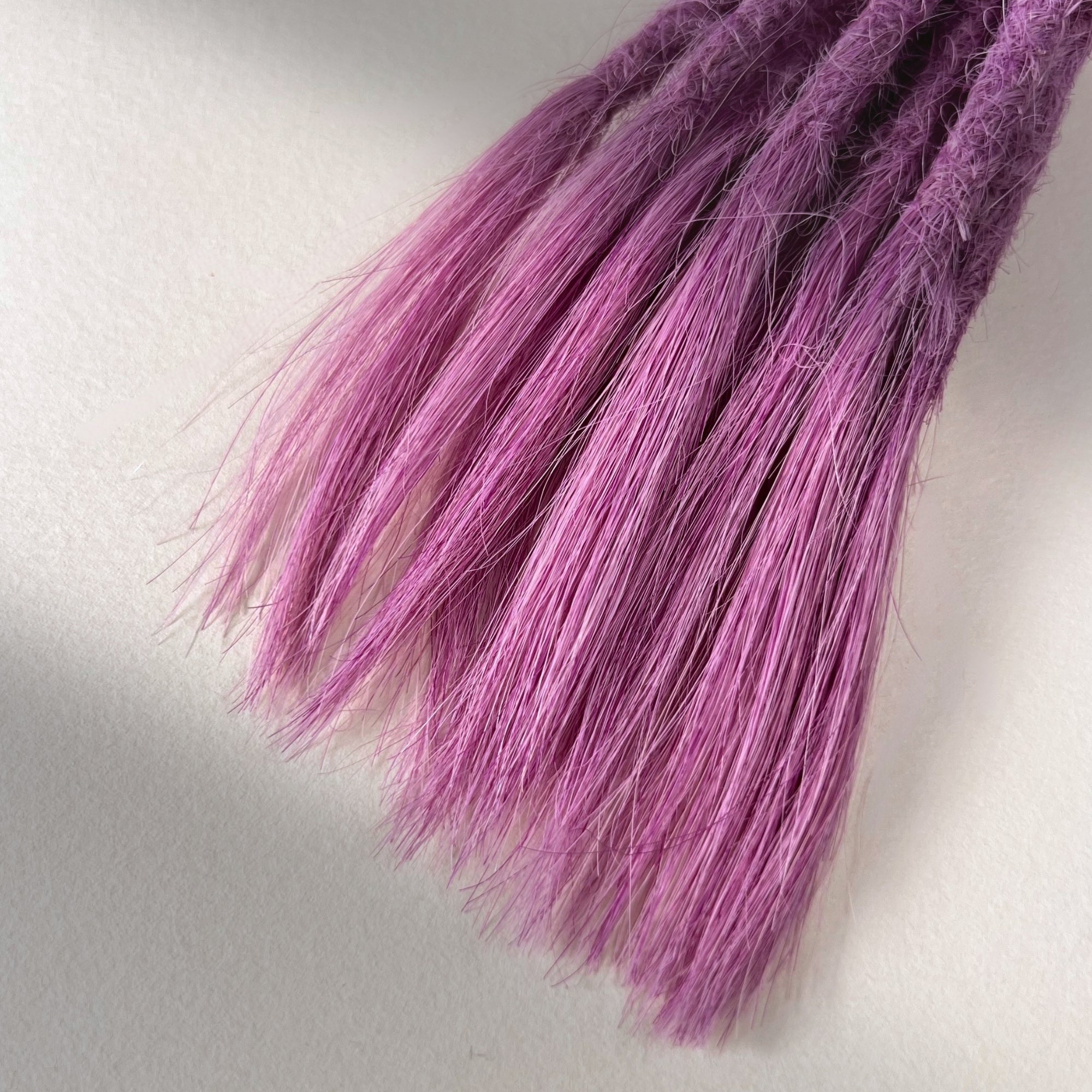 Tip detail of straight loc extensions with open ends in Lavender Purple.