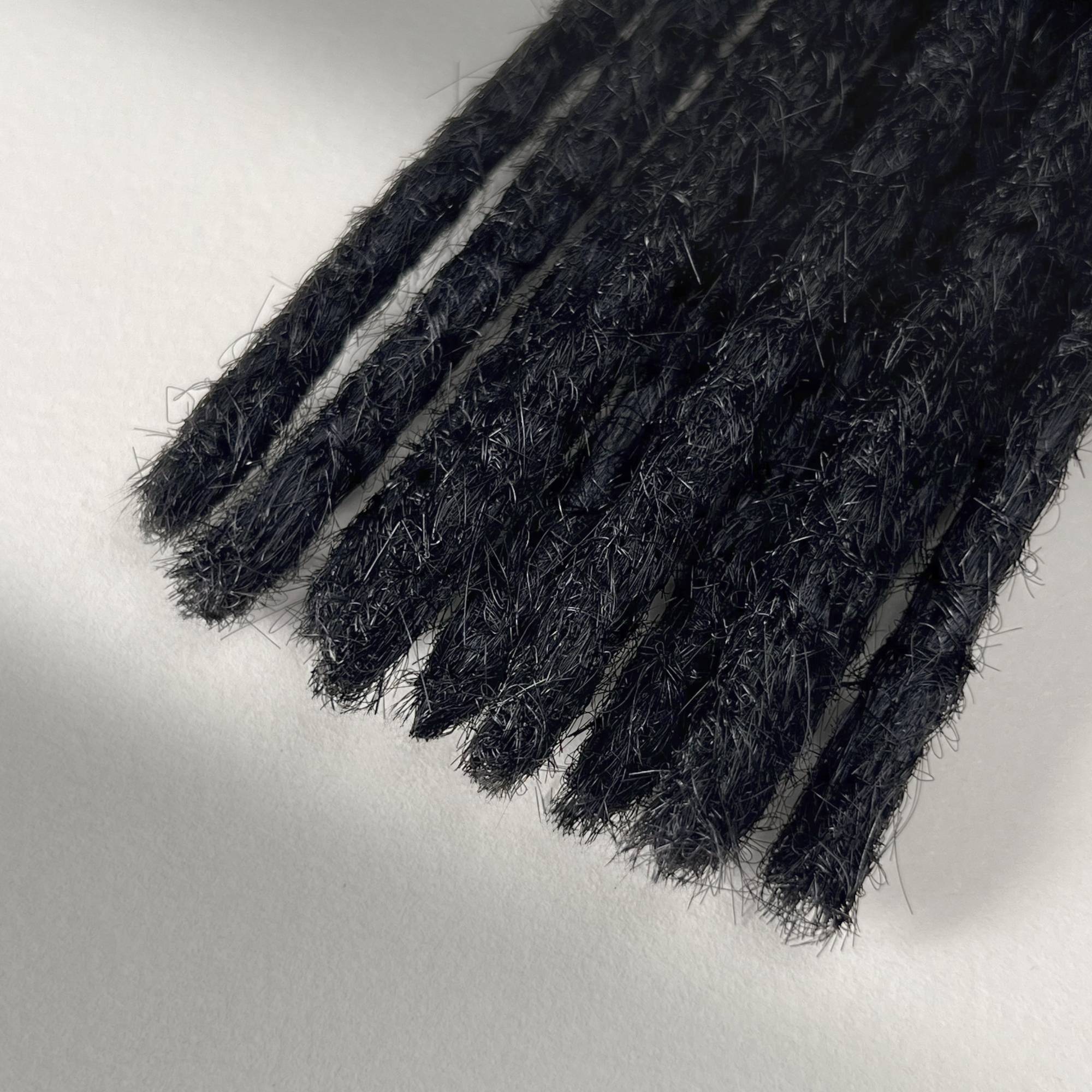 Tip detail of straight loc extensions with blunt ends in Deepest Black.