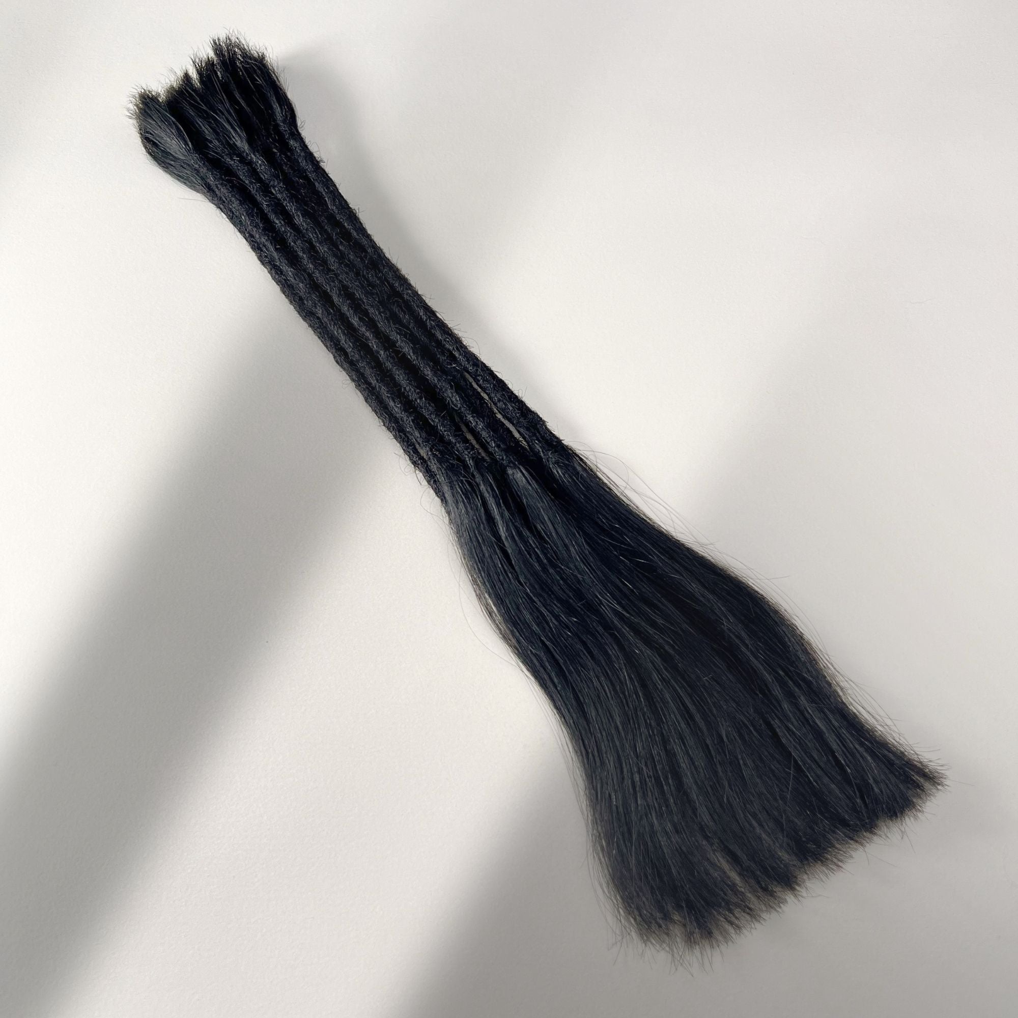 Full view of straight loc extensions with long loose ends in Deepest Black for permanent installation.