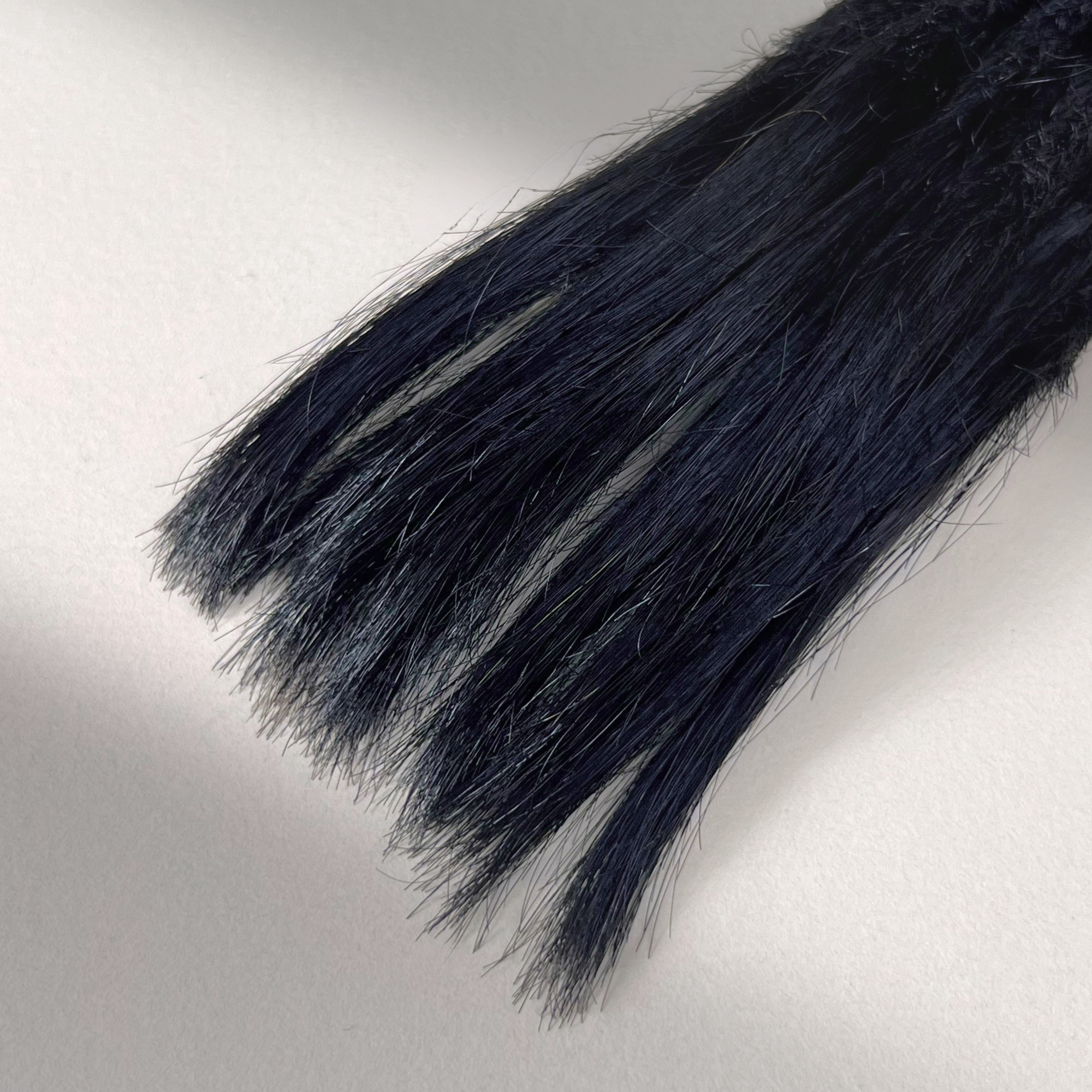 Tip detail of straight loc extensions with open ends in Deepest Black.