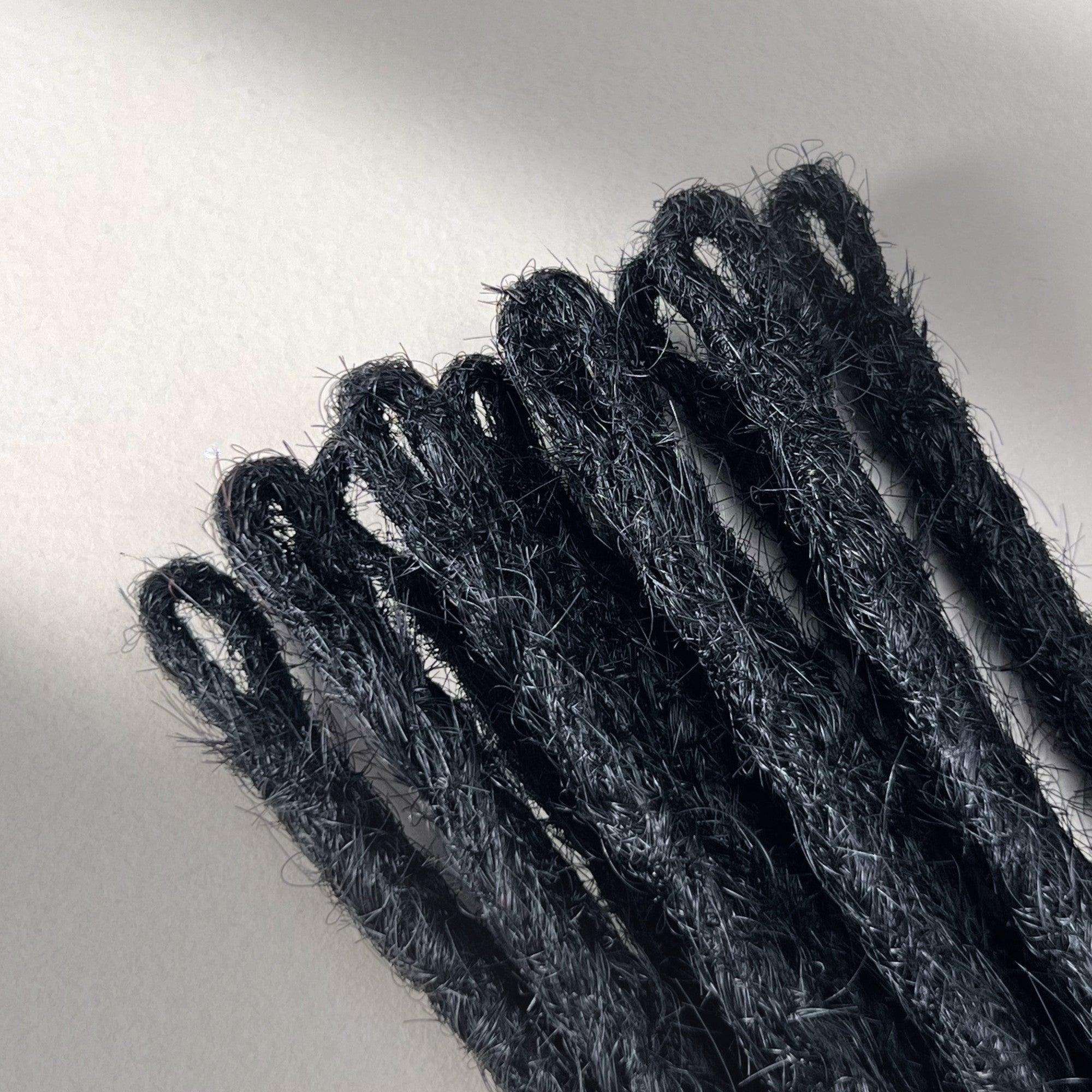 Loop detail of temporary single-ended straight loc extensions with open ends in Deepest Black.