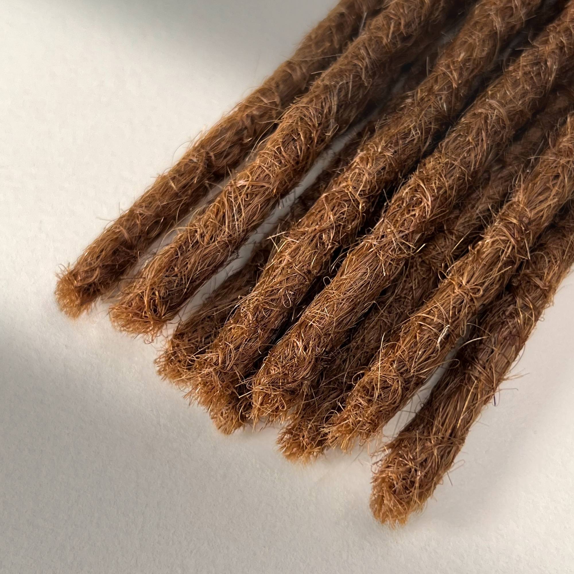 Tip detail of straight loc extensions with blunt ends in Auburn Copper.