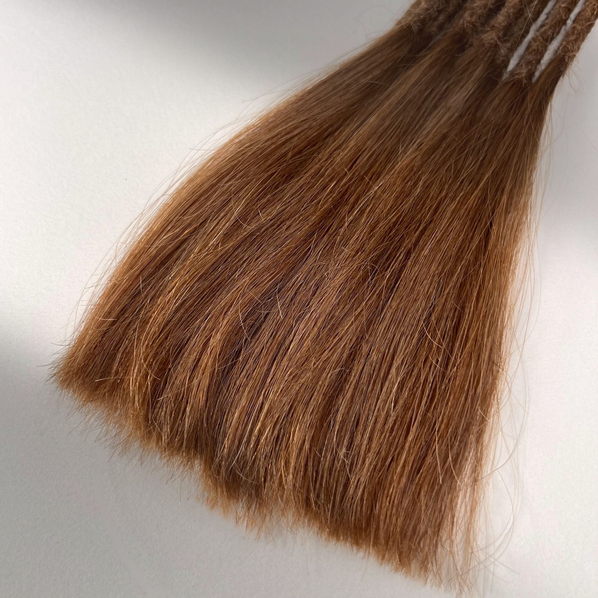 Tip detail of straight loc extensions with long loose ends in Auburn Copper.