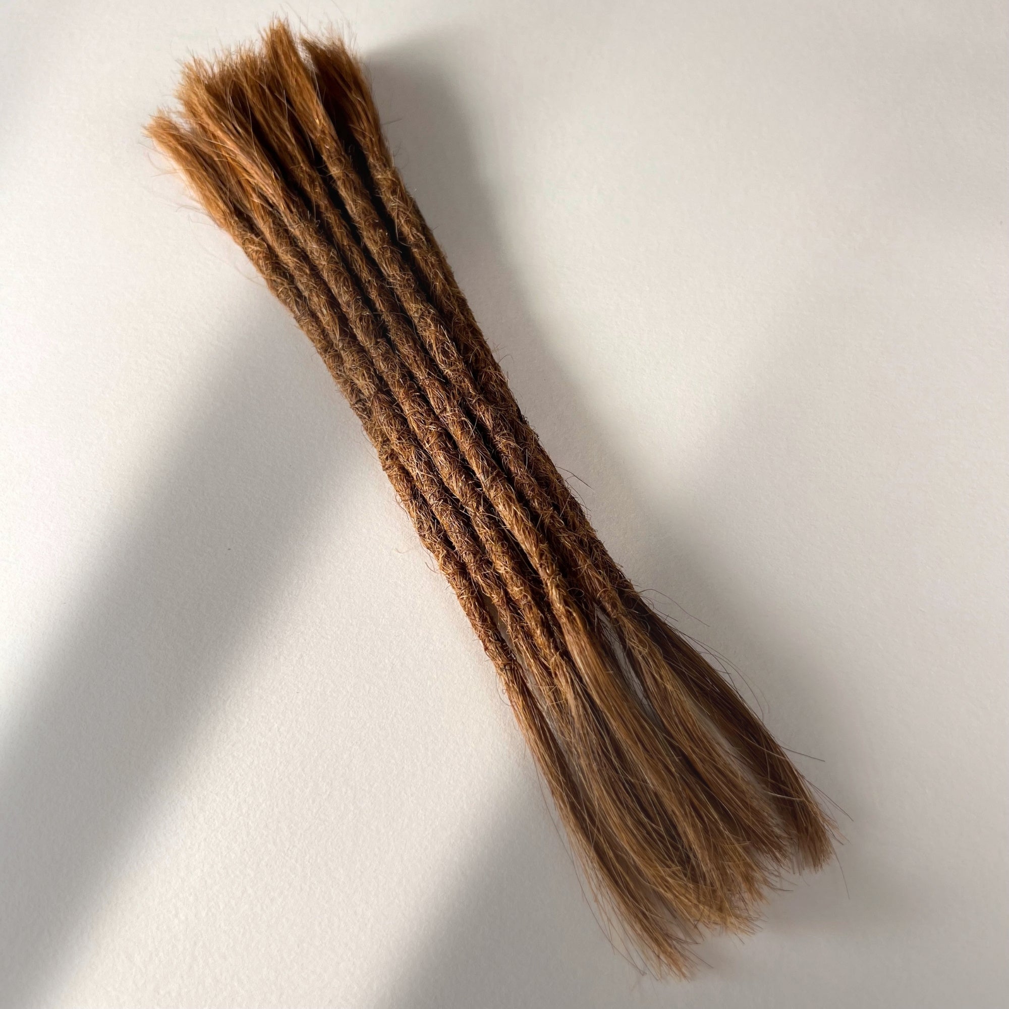 Full view of permanent straight loc extensions with open ends in Auburn Copper.