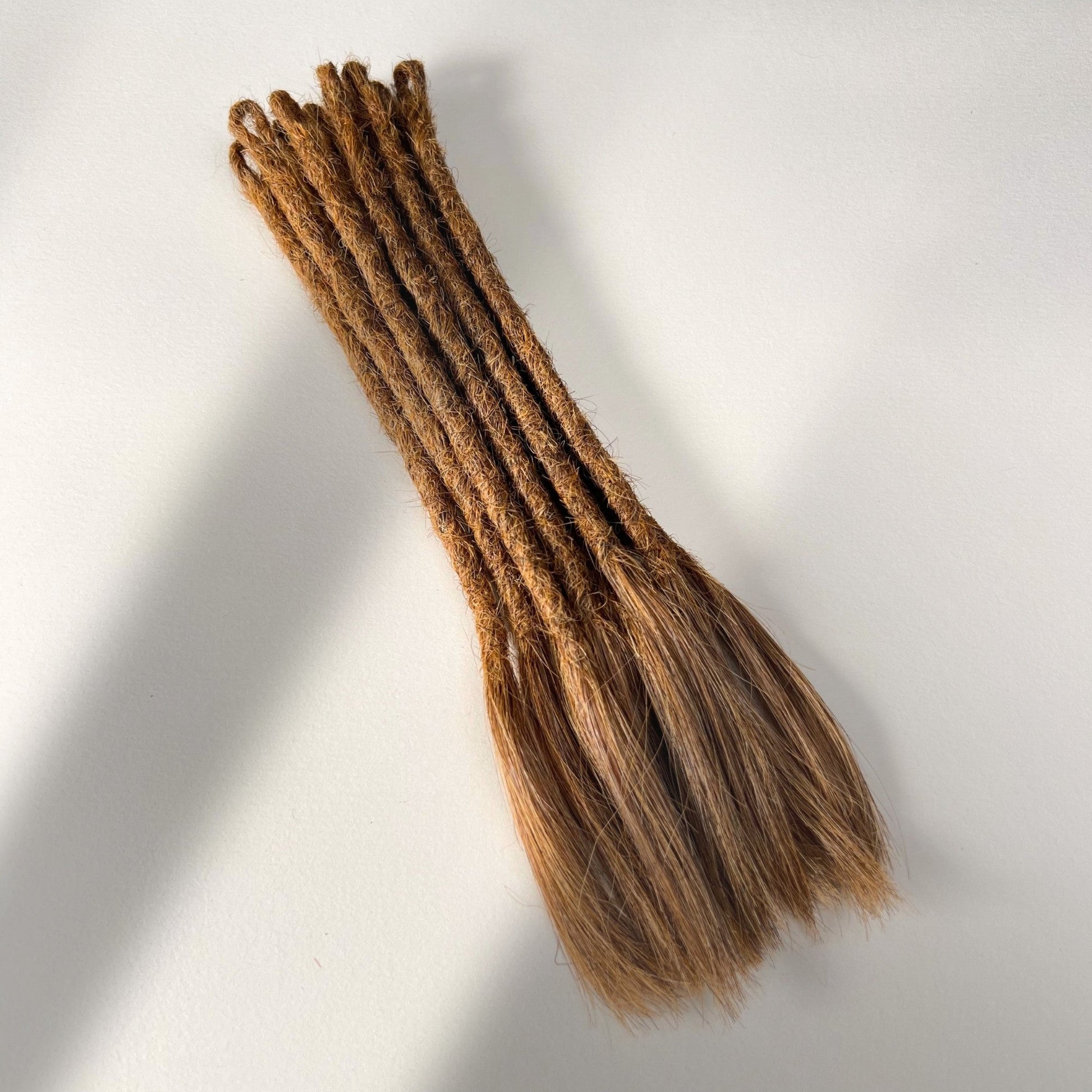 Full view of temporary single-ended straight loc extensions with open ends in Auburn Copper.