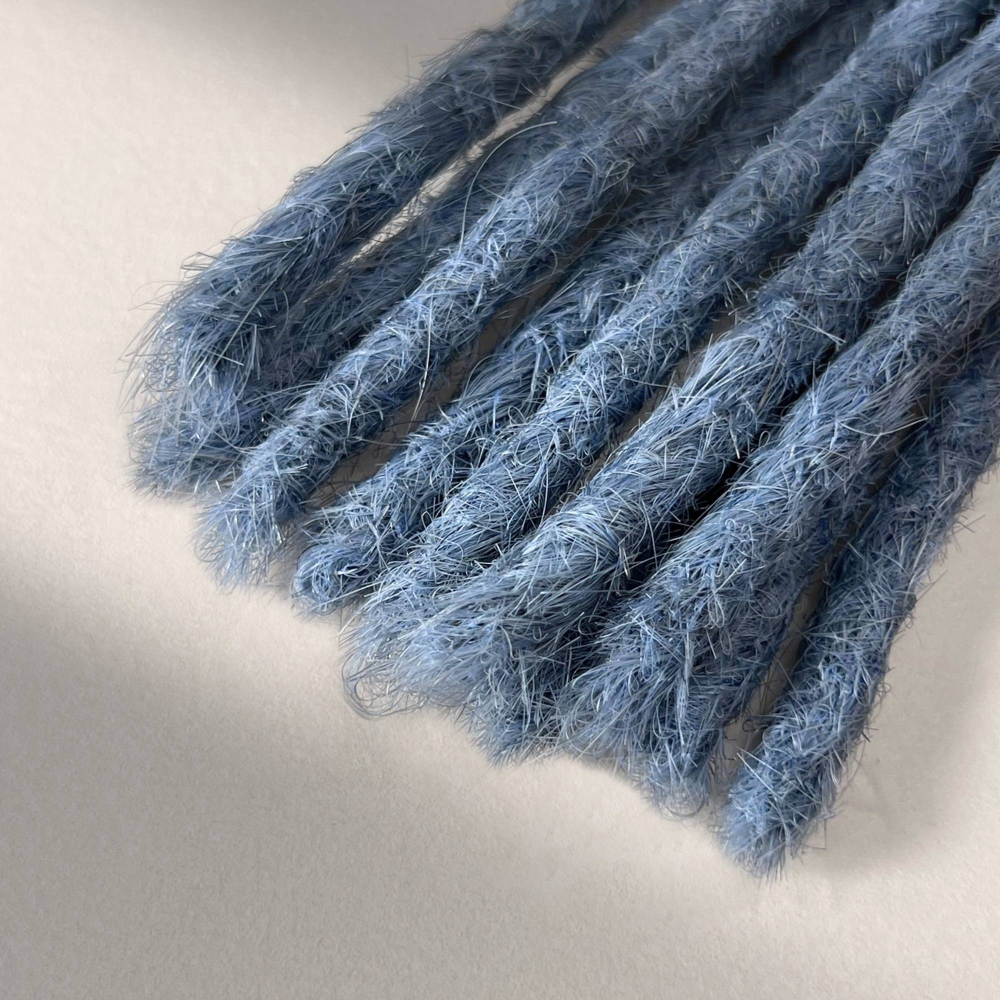 Tip detail of straight loc extensions with blunt ends in Sky Blue.