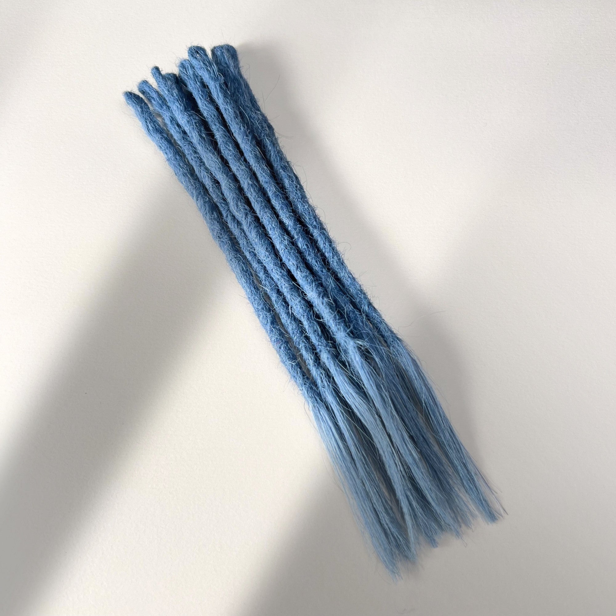 Full view of temporary single-ended straight loc extensions with open ends in Sky Blue.