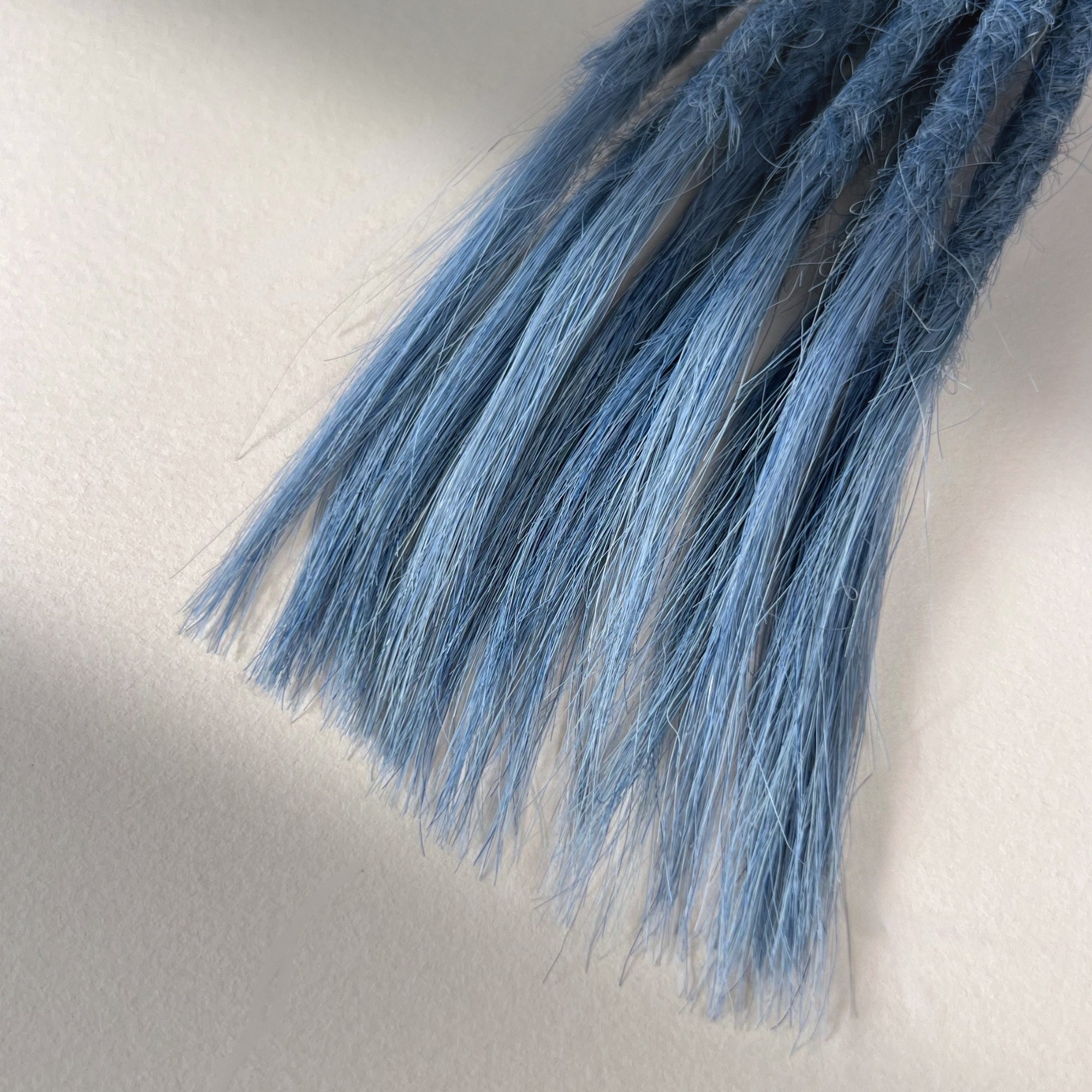 Tip detail of straight loc extensions with open ends in Sky Blue.