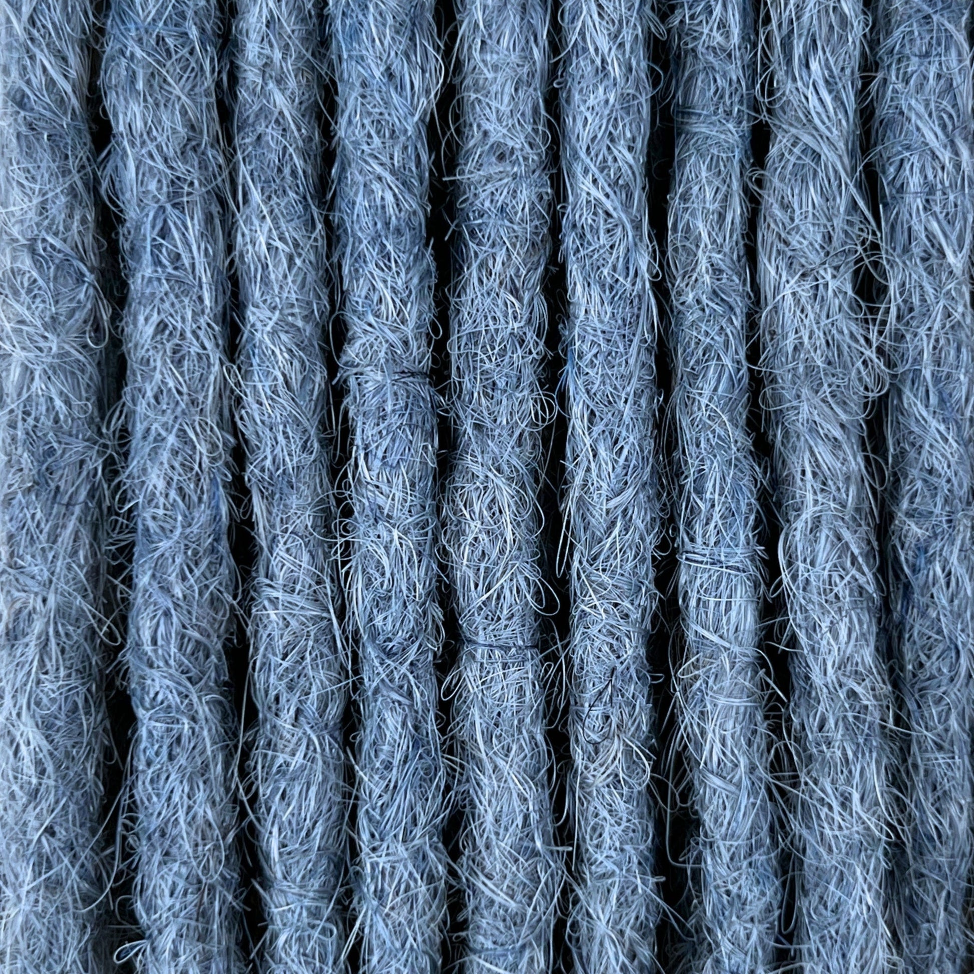 Close-up of straight loc extensions in Sky Blue, showing the texture and color.