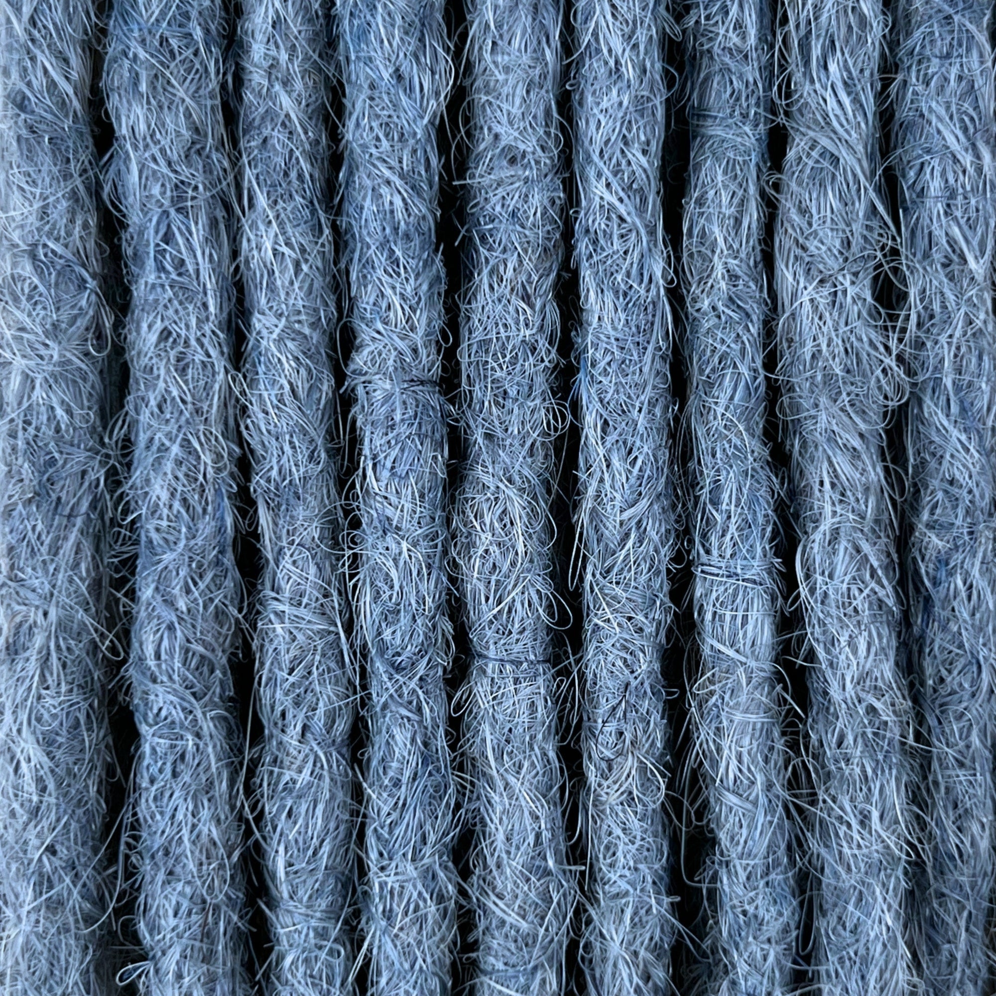 Close-up of straight loc extensions in Sky Blue, showing the texture and color.