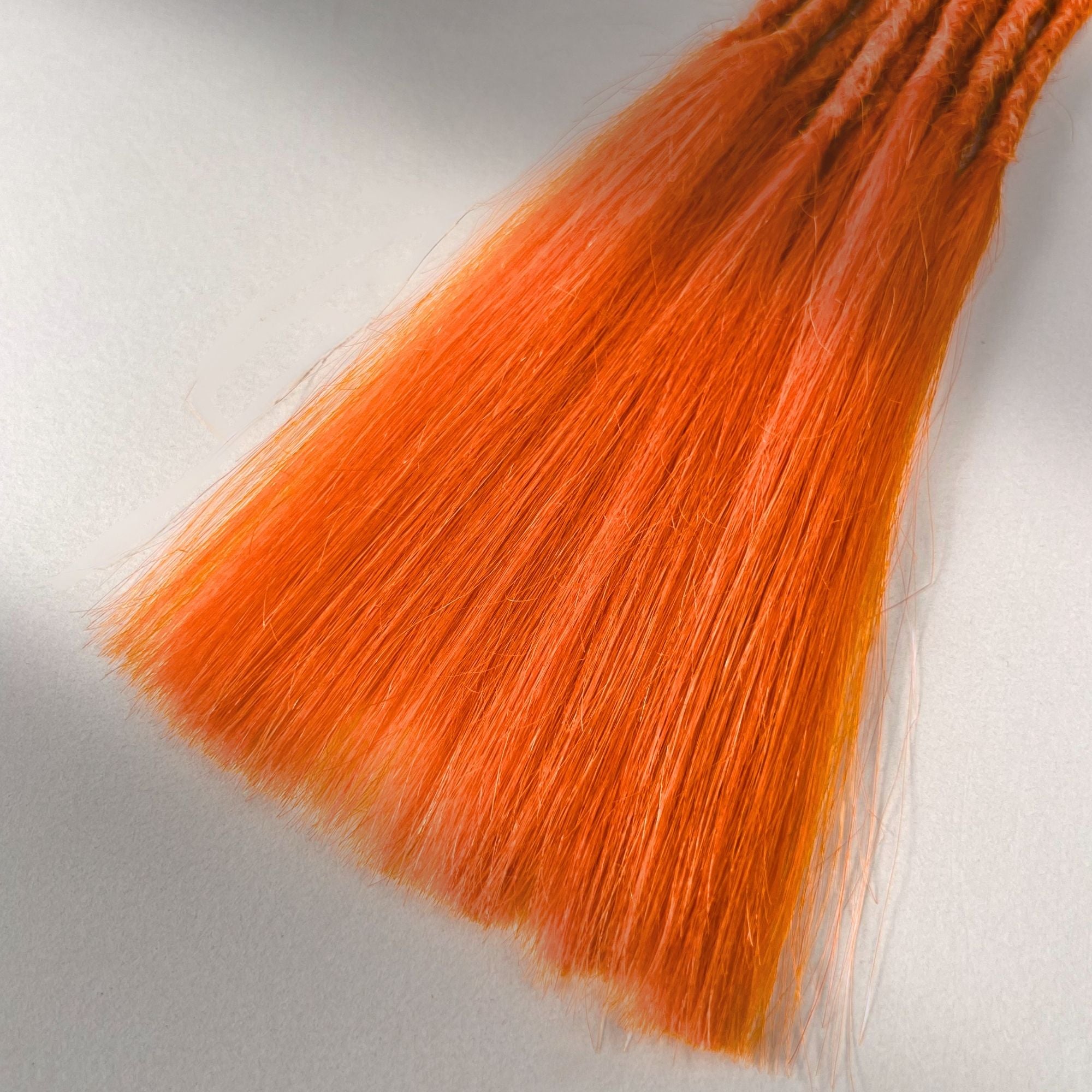 Tip detail of straight loc extensions with long loose ends in Burnt Orange.