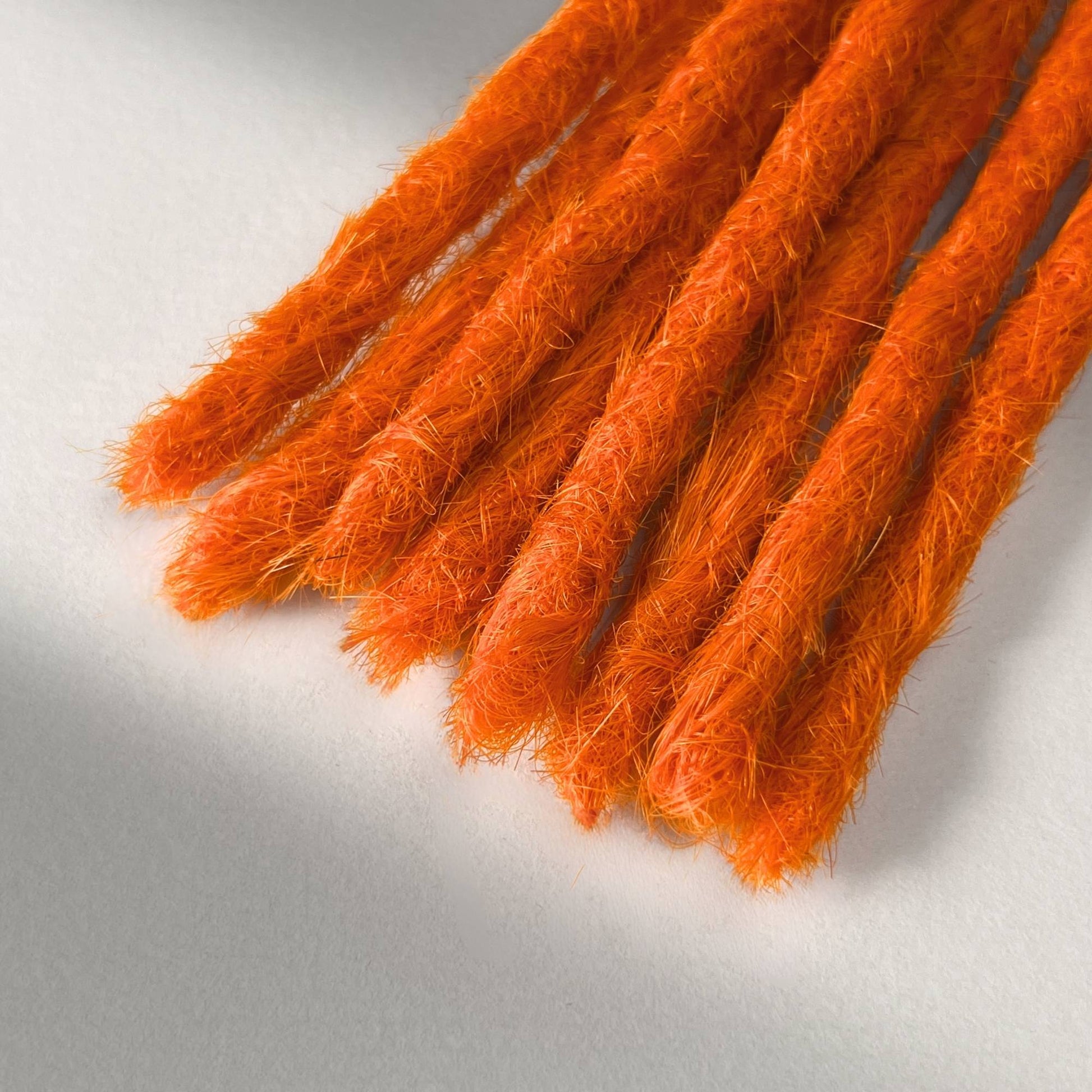 Tip detail of straight loc extensions with blunt ends in Burnt Orange.
