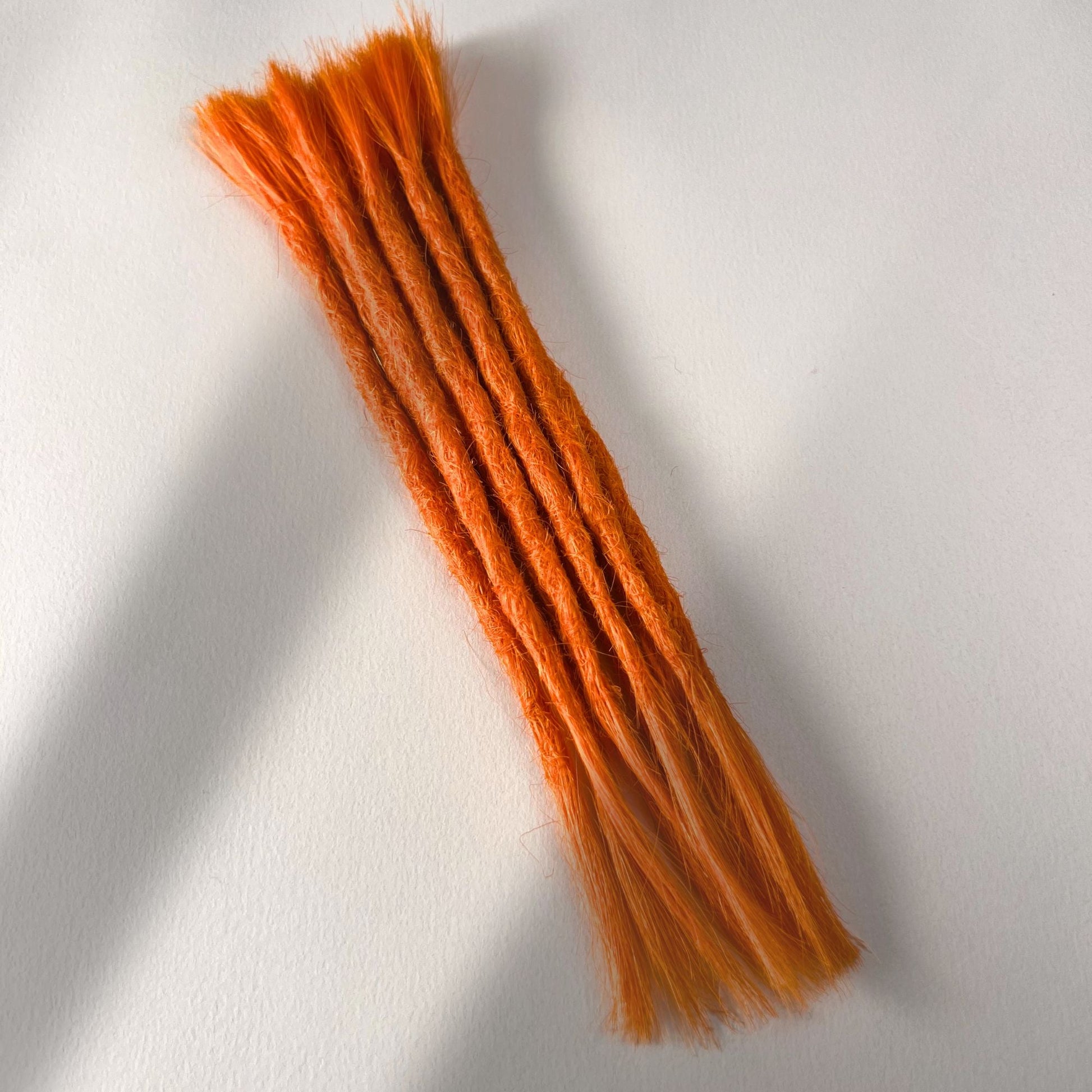 Full view of permanent straight loc extensions with open ends in Burnt Orange.