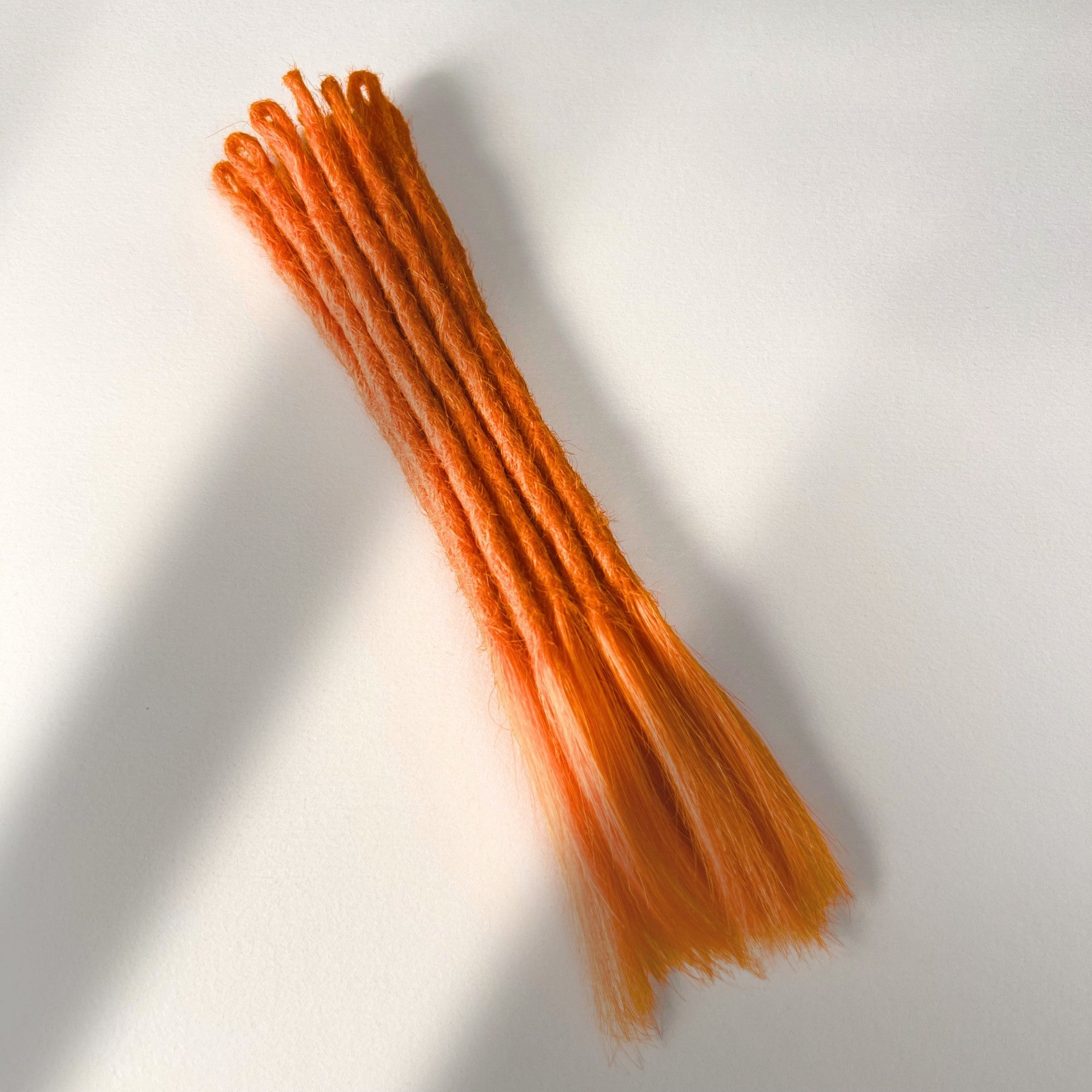 Full view of temporary single-ended straight loc extensions with open ends in Burnt Orange.