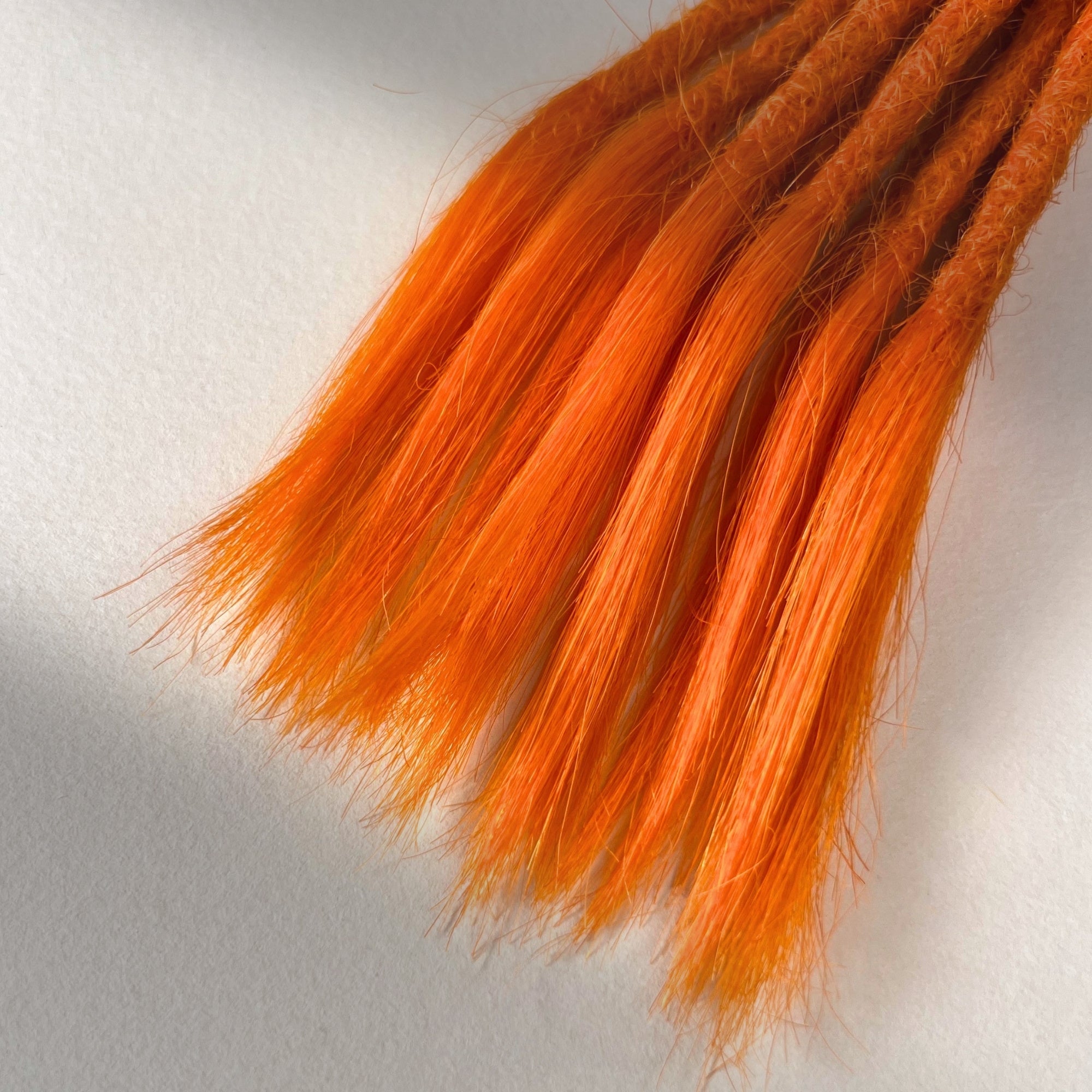 Tip detail of straight loc extensions with open ends in Burnt Orange.