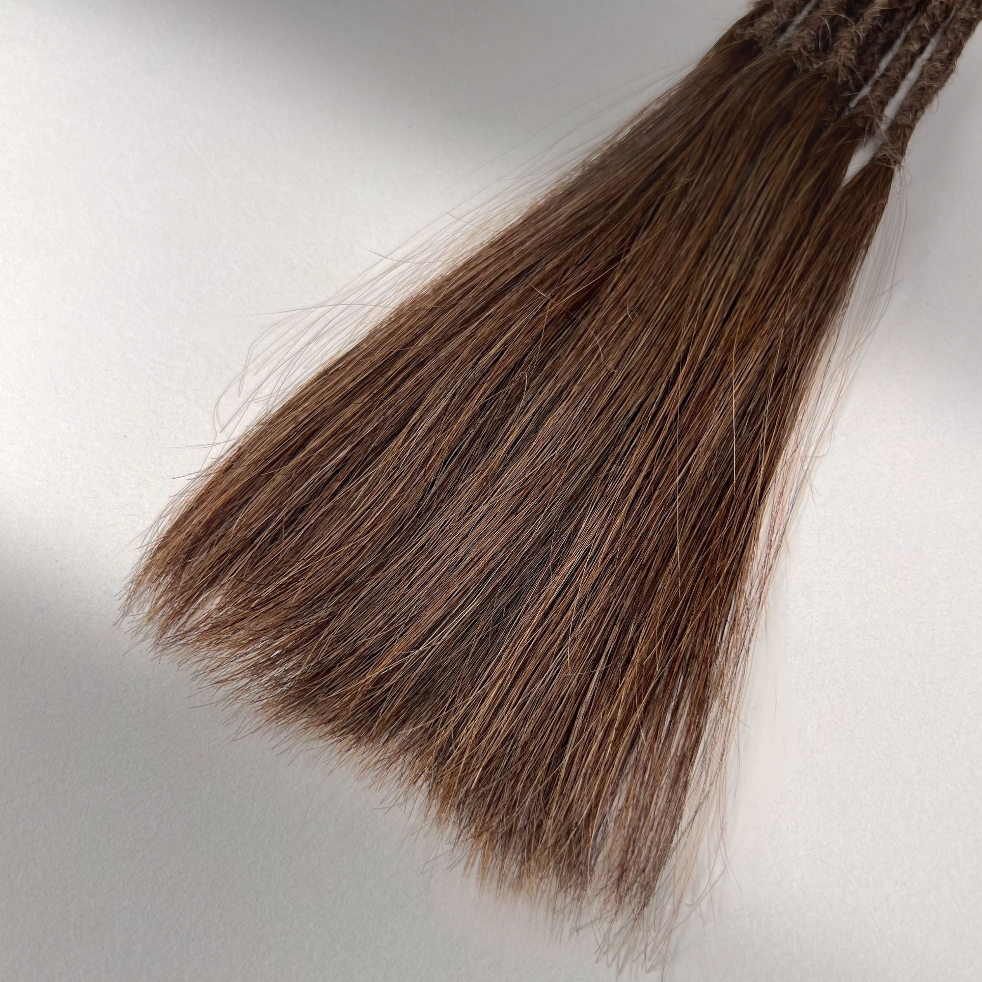 Tip detail of straight loc extensions with long loose ends in Warm Cinnamon Brown.