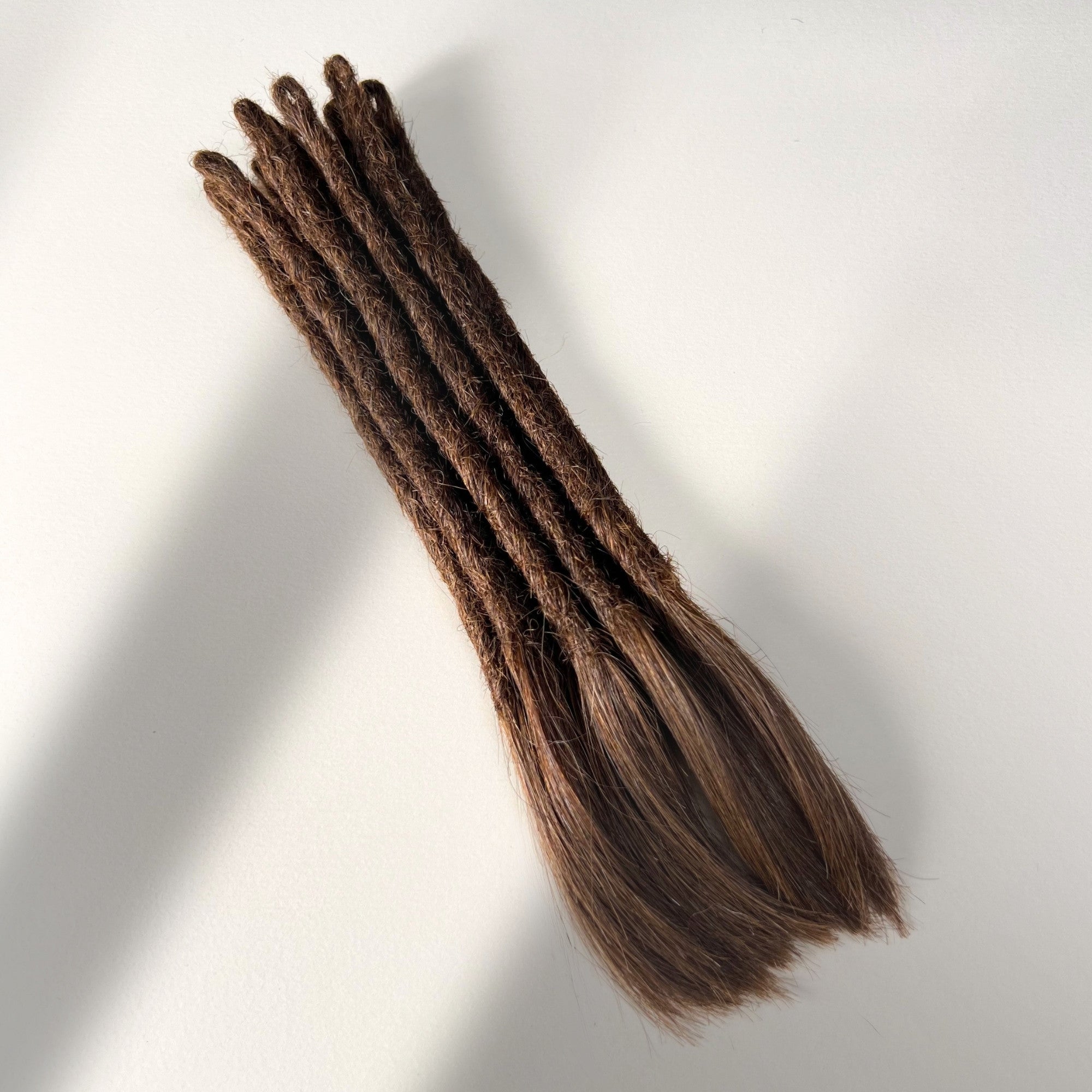 Full view of temporary single-ended straight loc extensions with open ends in Warm Cinnamon Brown.