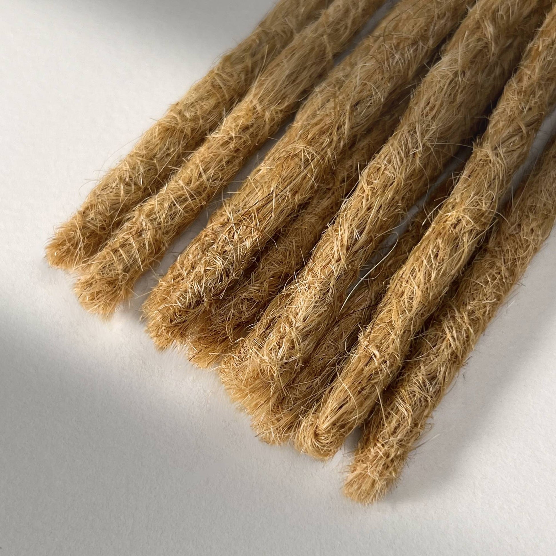 Tip detail of straight loc extensions with blunt ends in Sunkissed Blonde.