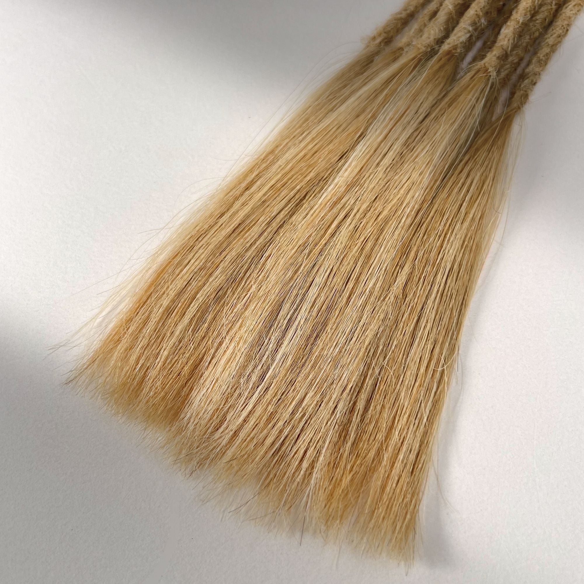 Tip detail of straight loc extensions with long loose ends in Sunkissed Blonde.