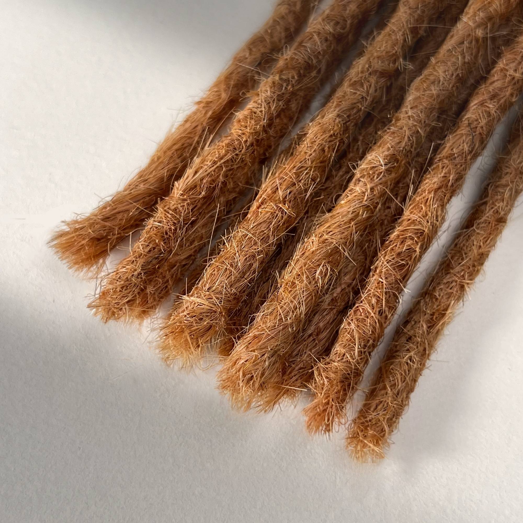 Tip detail of straight loc extensions with blunt ends in Warm Copper Blonde.