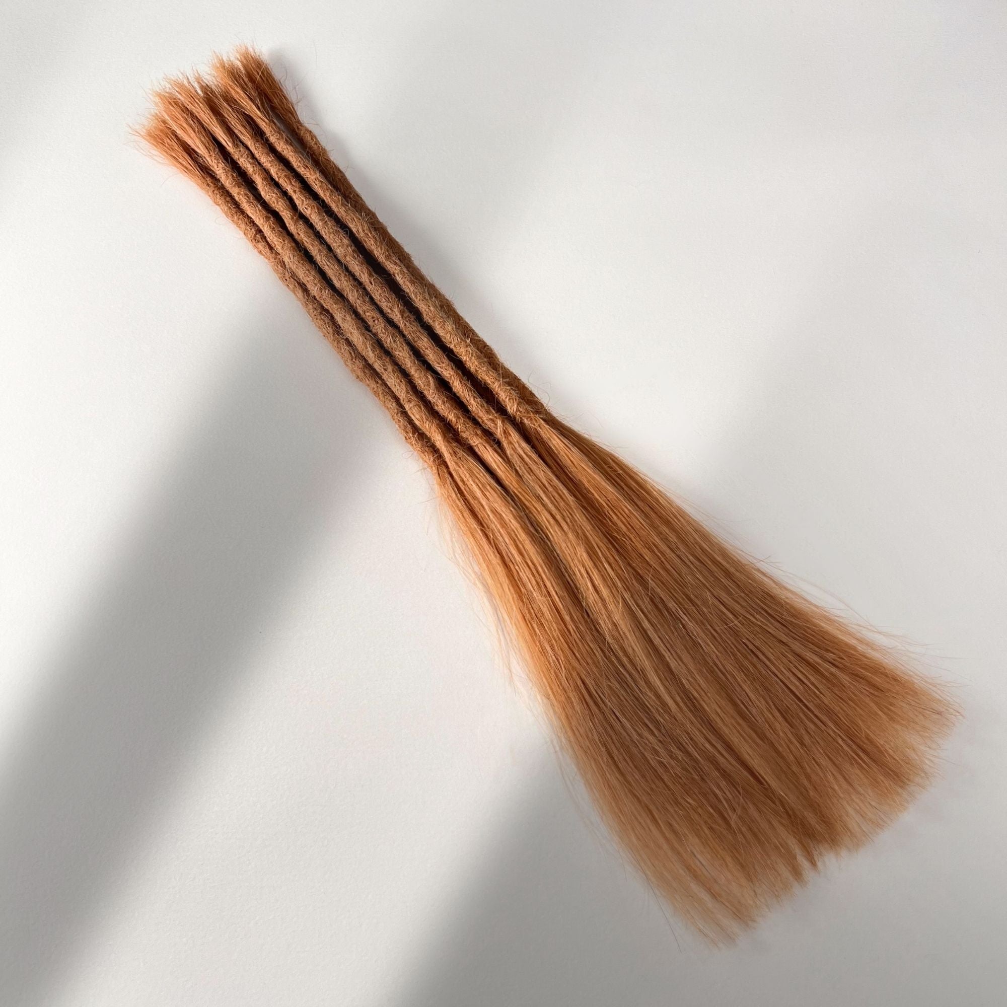 Full view of permanent straight loc extensions with long loose ends in Warm Copper Blonde.