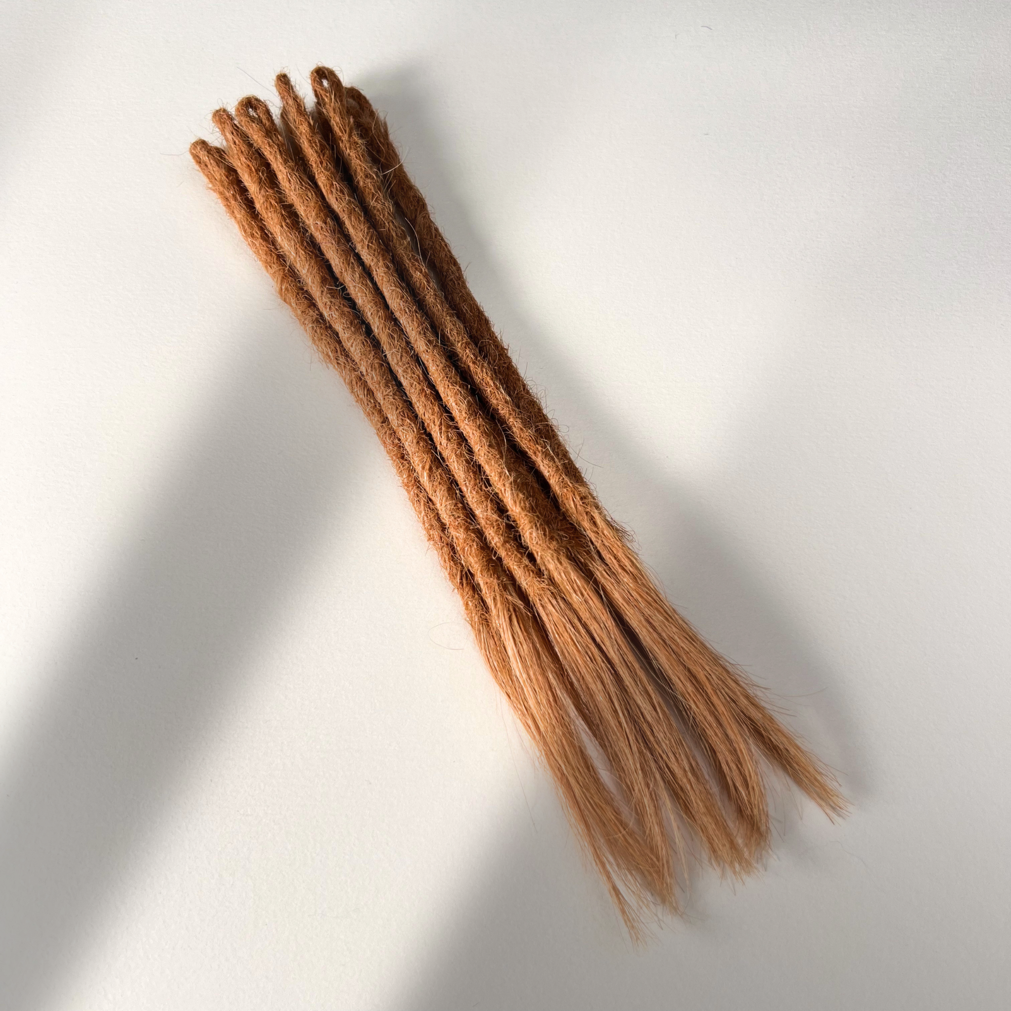 Full view of temporary single-ended straight loc extensions with open ends in Warm Copper Blonde.
