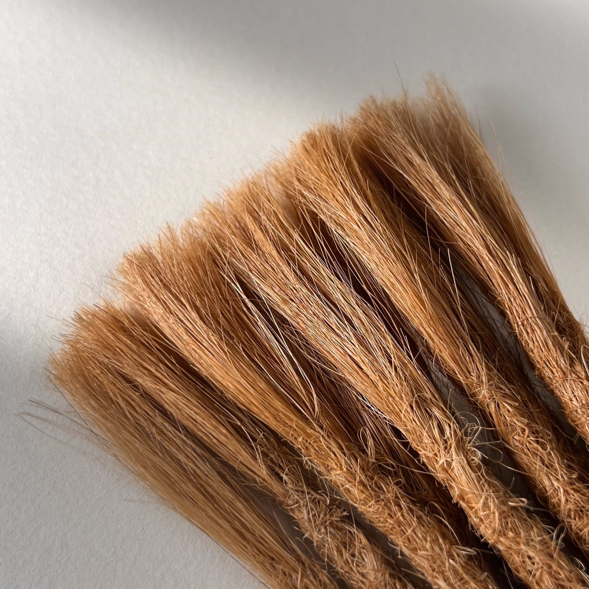 Connection point of permanent straight loc extensions in Warm Copper Blonde.