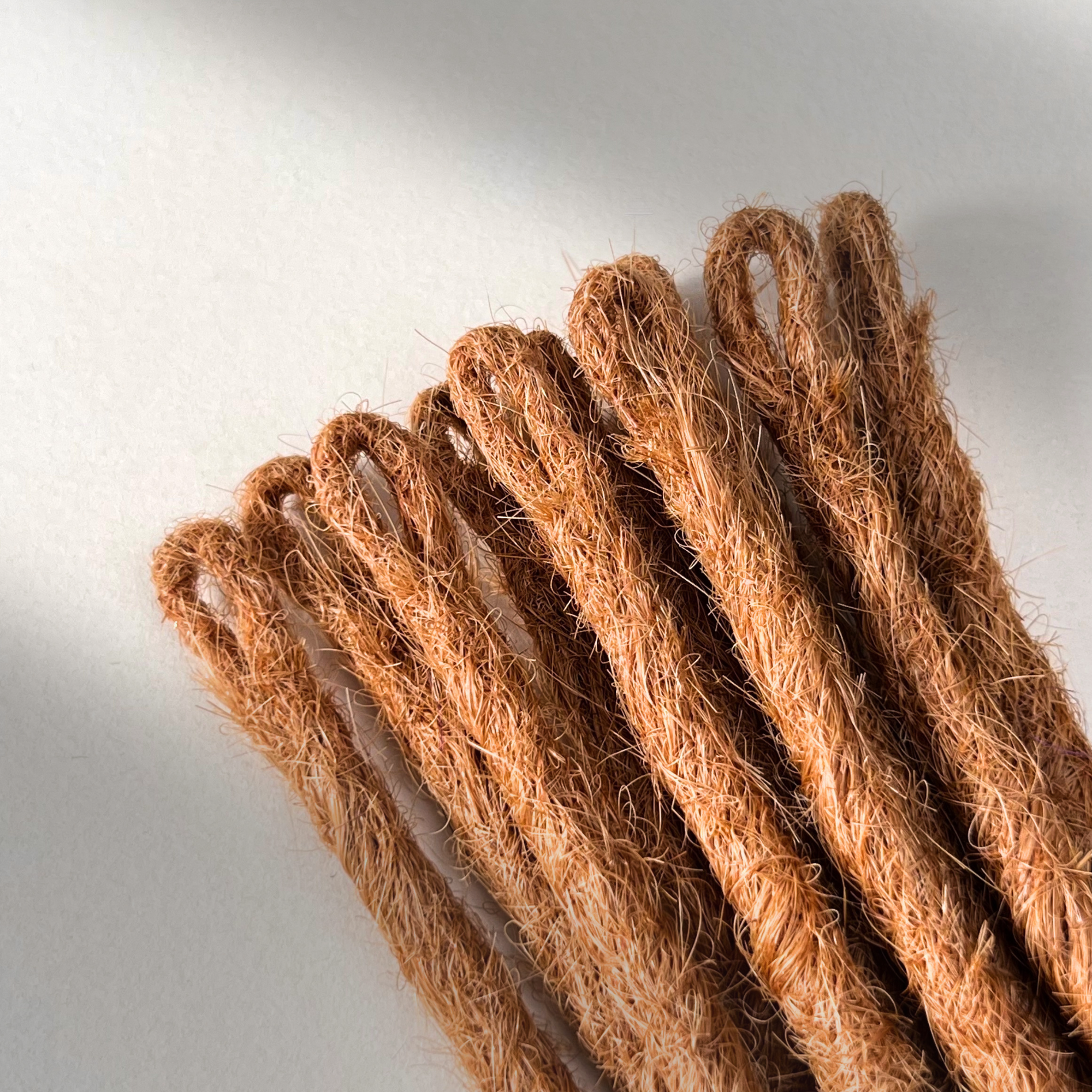 Loop detail of temporary single-ended straight loc extensions in Warm Copper Blonde.