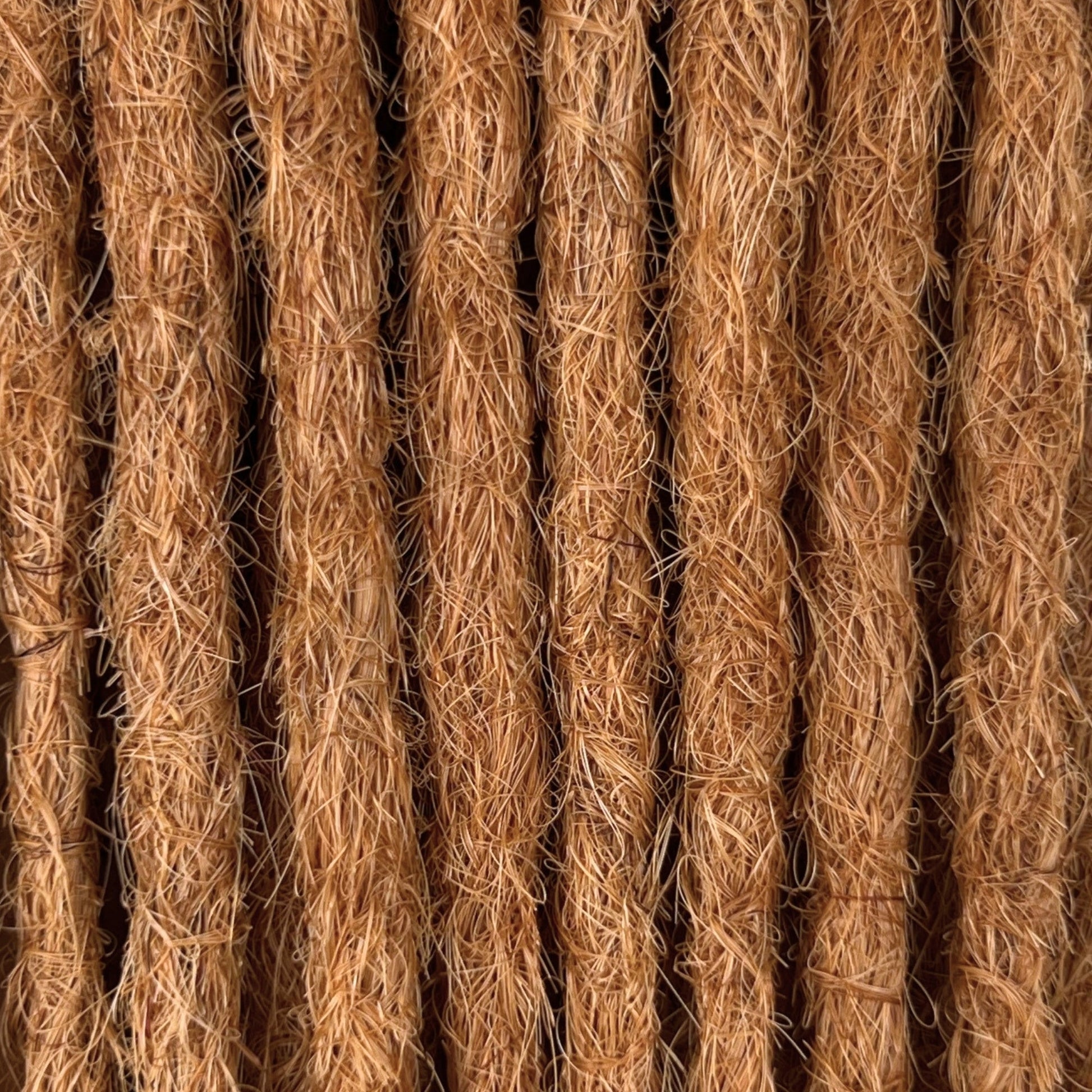 Close-up of straight loc extensions in Warm Copper Blonde, showing the texture and color.