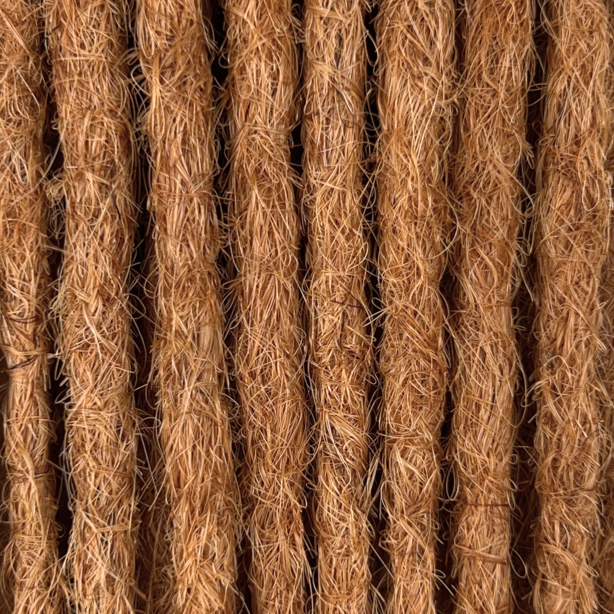 Close-up of straight loc extensions in Warm Copper Blonde, showing the texture and color.