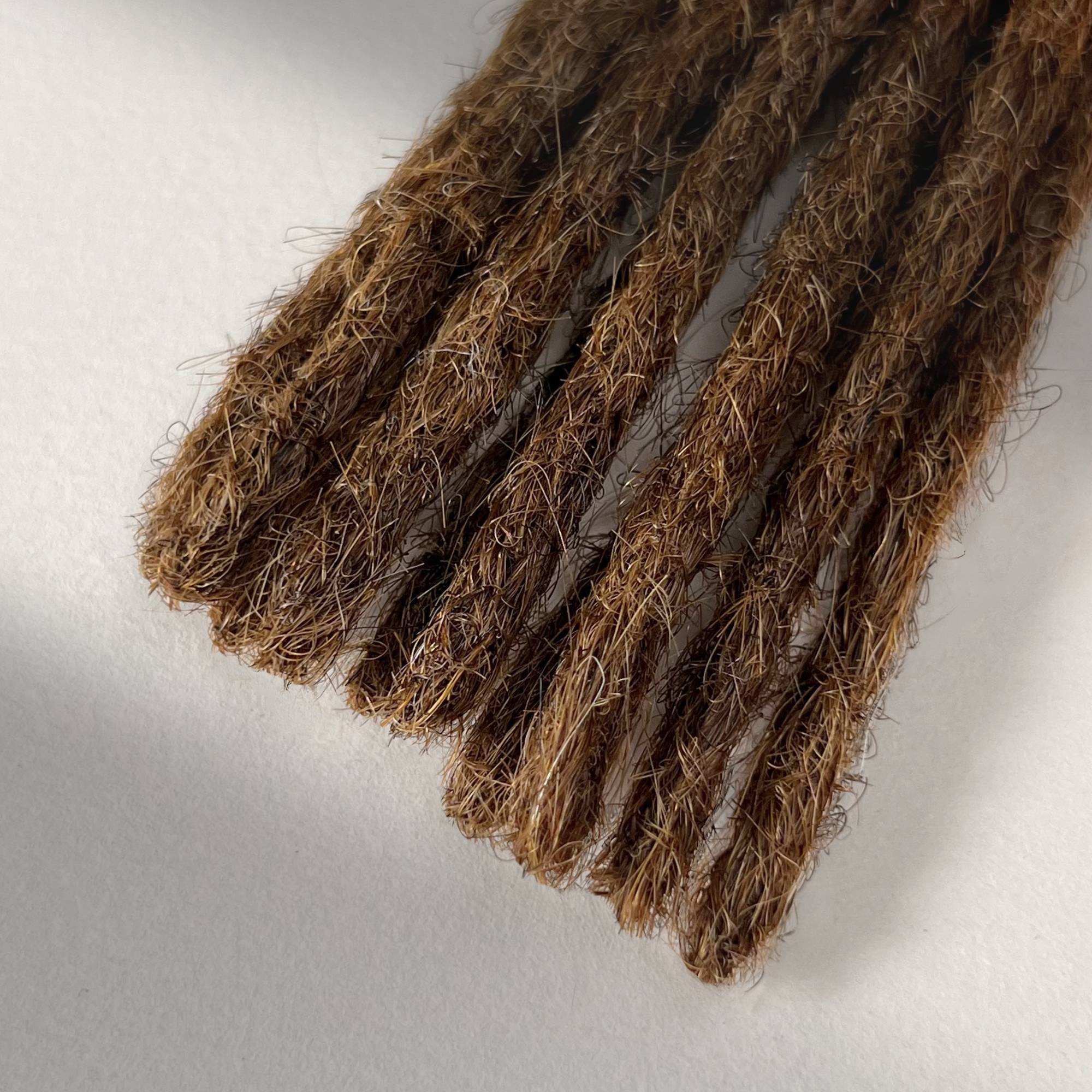 Tip detail of straight loc extensions with blunt ends in Warm Golden Brown.