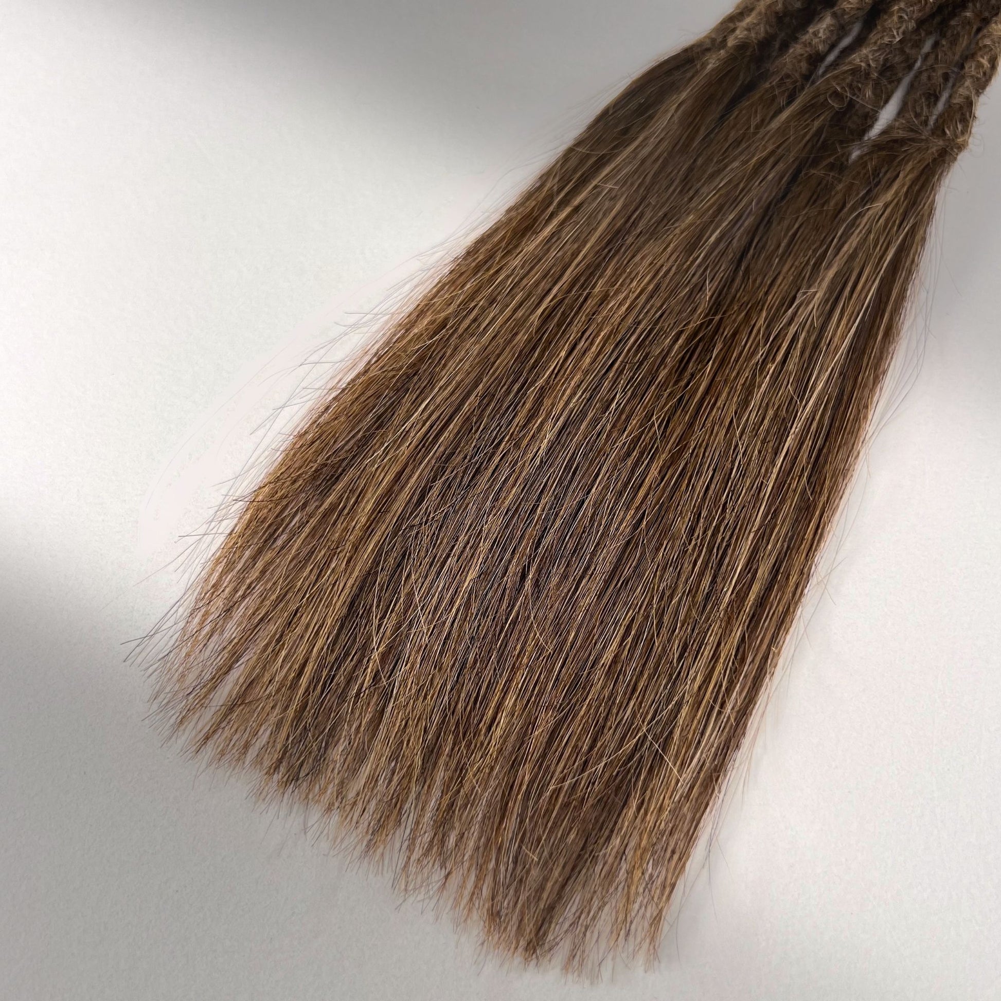 Tip detail of straight loc extensions with long loose ends in Warm Golden Brown.