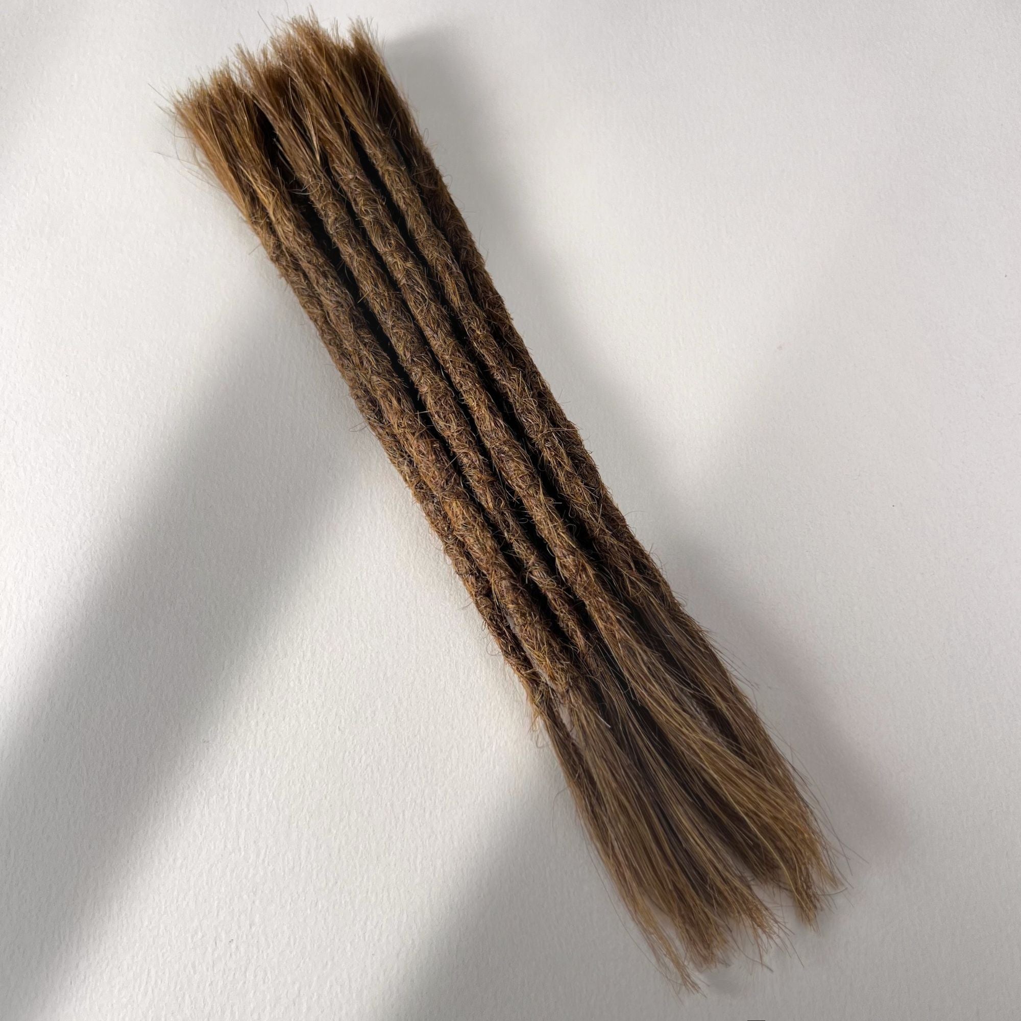 Full view of permanent straight loc extensions with open ends in Warm Golden Brown.